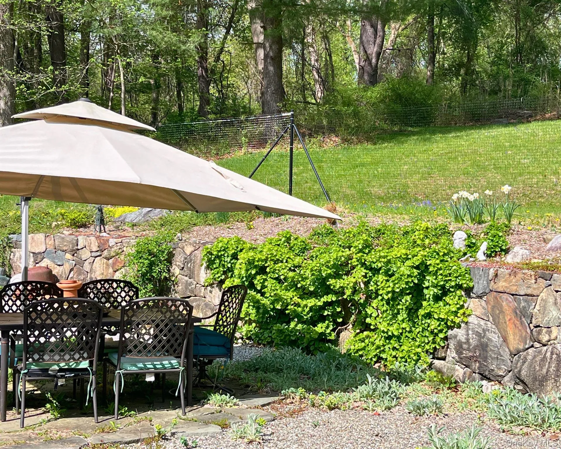 Patio with table, umbrella, and fire pit surrounded by lush landscaping Patio with table, umbrella, and fire pit surrounded by lush landscaping