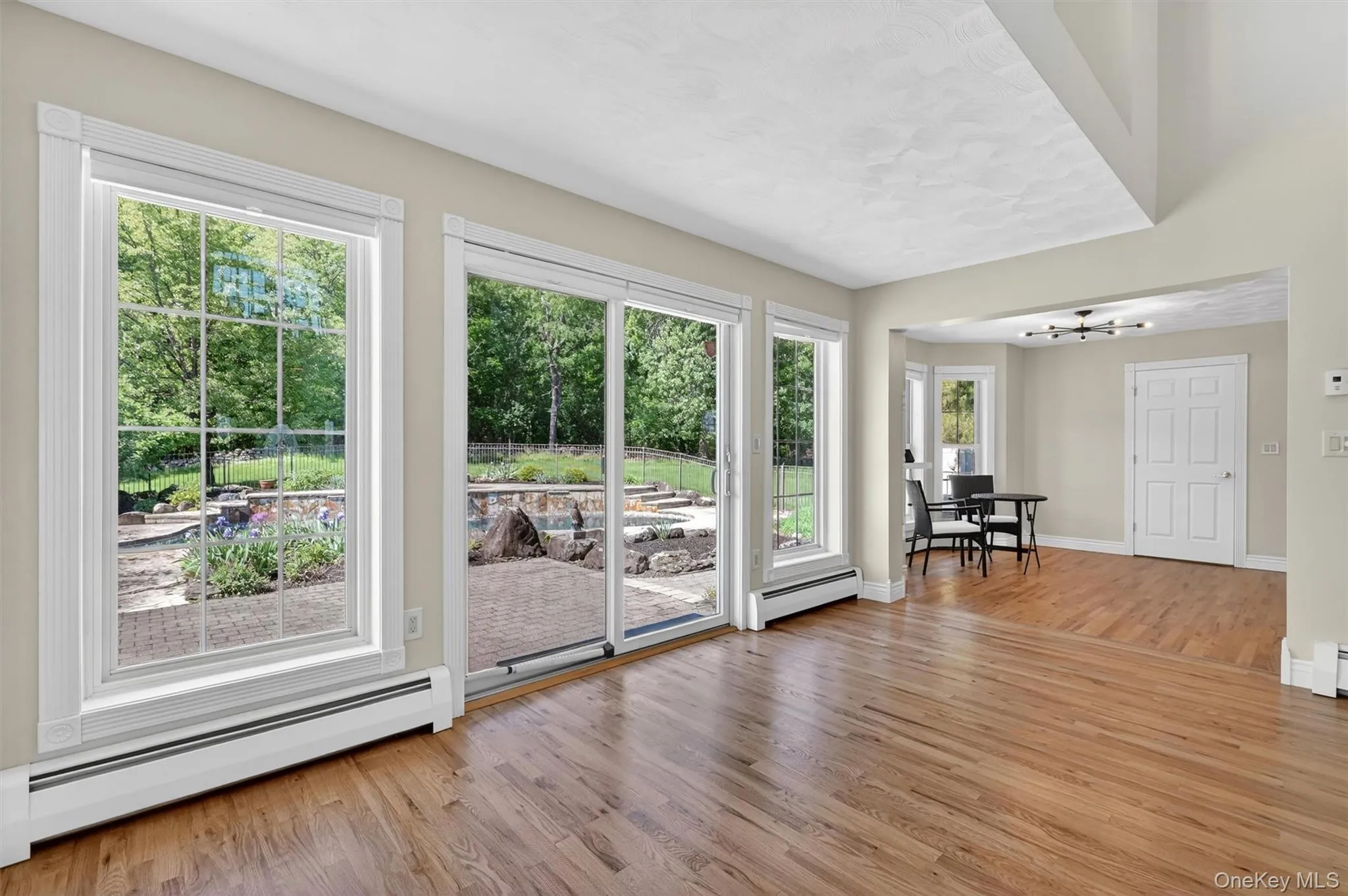 Large windows and glass doors bring the outside in, offering views of the patio, stonework, and backyard retreat. Large windows and glass doors bring the outside in, offering views of the patio, stonework, and backyard retreat.