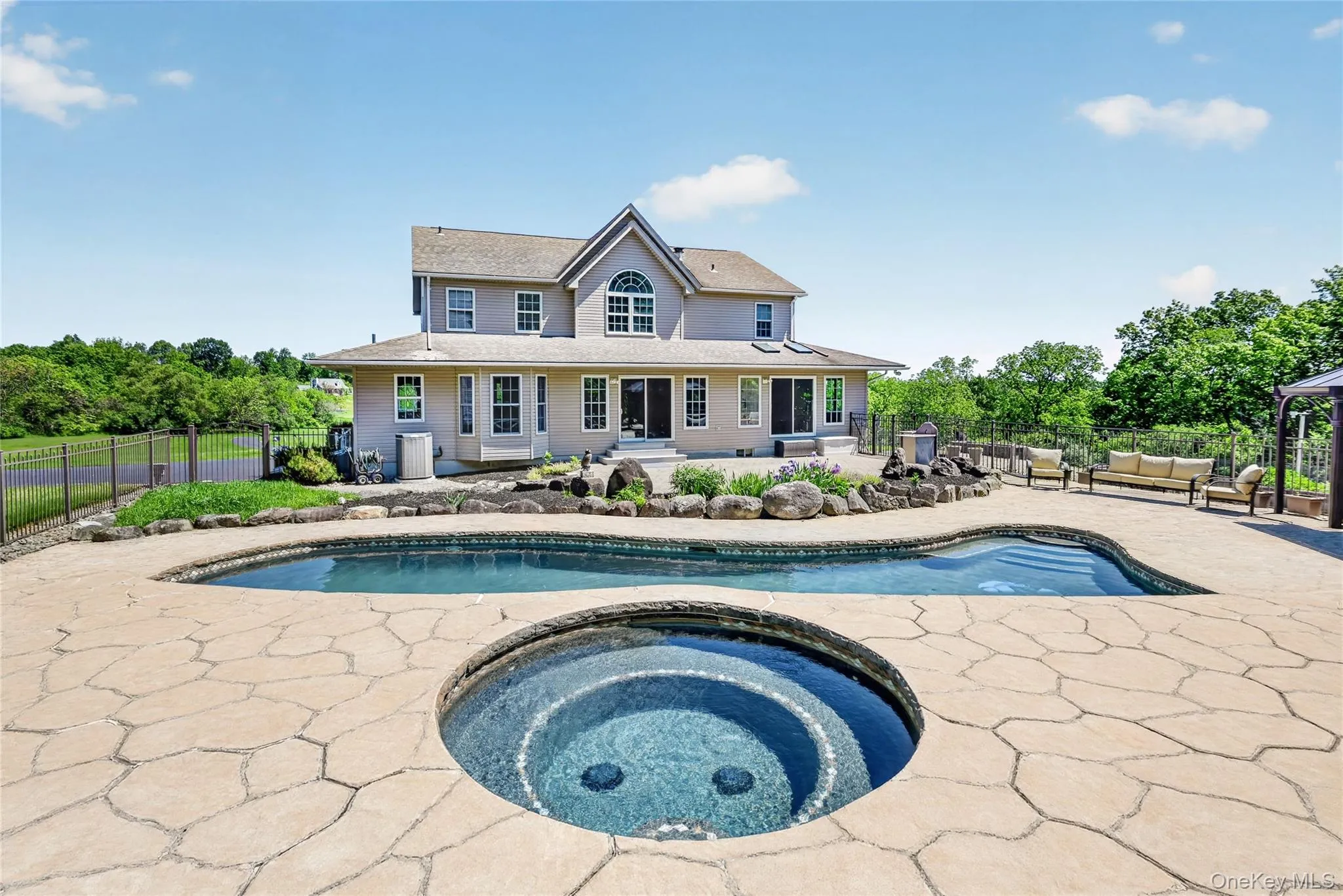 From this angle, the resort-like pool area truly shines, with the heated gunite pool, raised hot tub, and waterfall features creating the perfect backdrop for summer days, evening swims, and memorable gatherings at home. From this angle, the resort-like pool area truly shines, with the heated gunite pool, raised hot tub, and waterfall features creating the perfect backdrop for summer days, evening swims, and memorable gatherings at home.