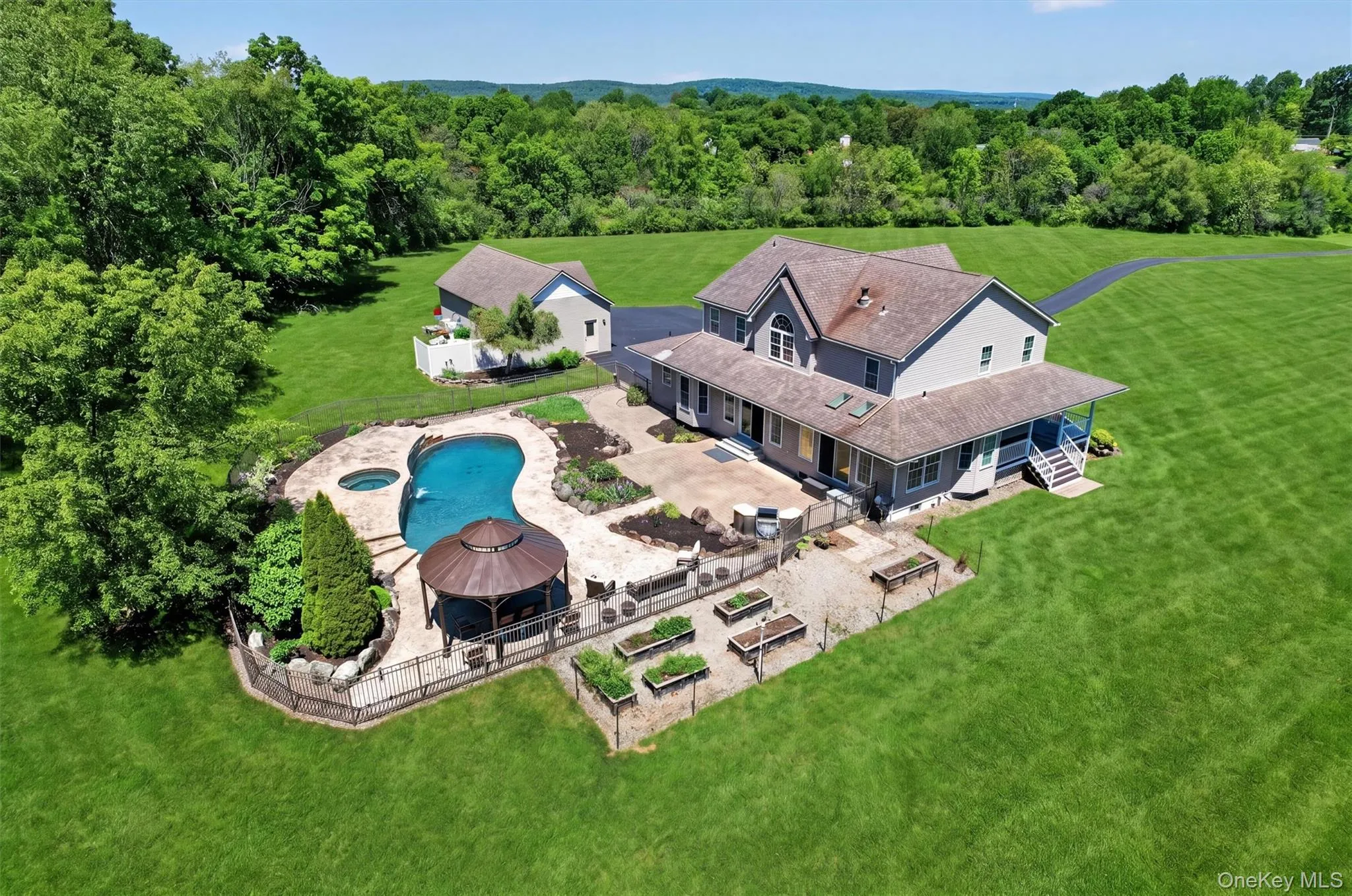 This aerial view captures how beautifully the home, pool, patio, gardens, garage, and open lawn all come together into one peaceful setting. This aerial view captures how beautifully the home, pool, patio, gardens, garage, and open lawn all come together into one peaceful setting.