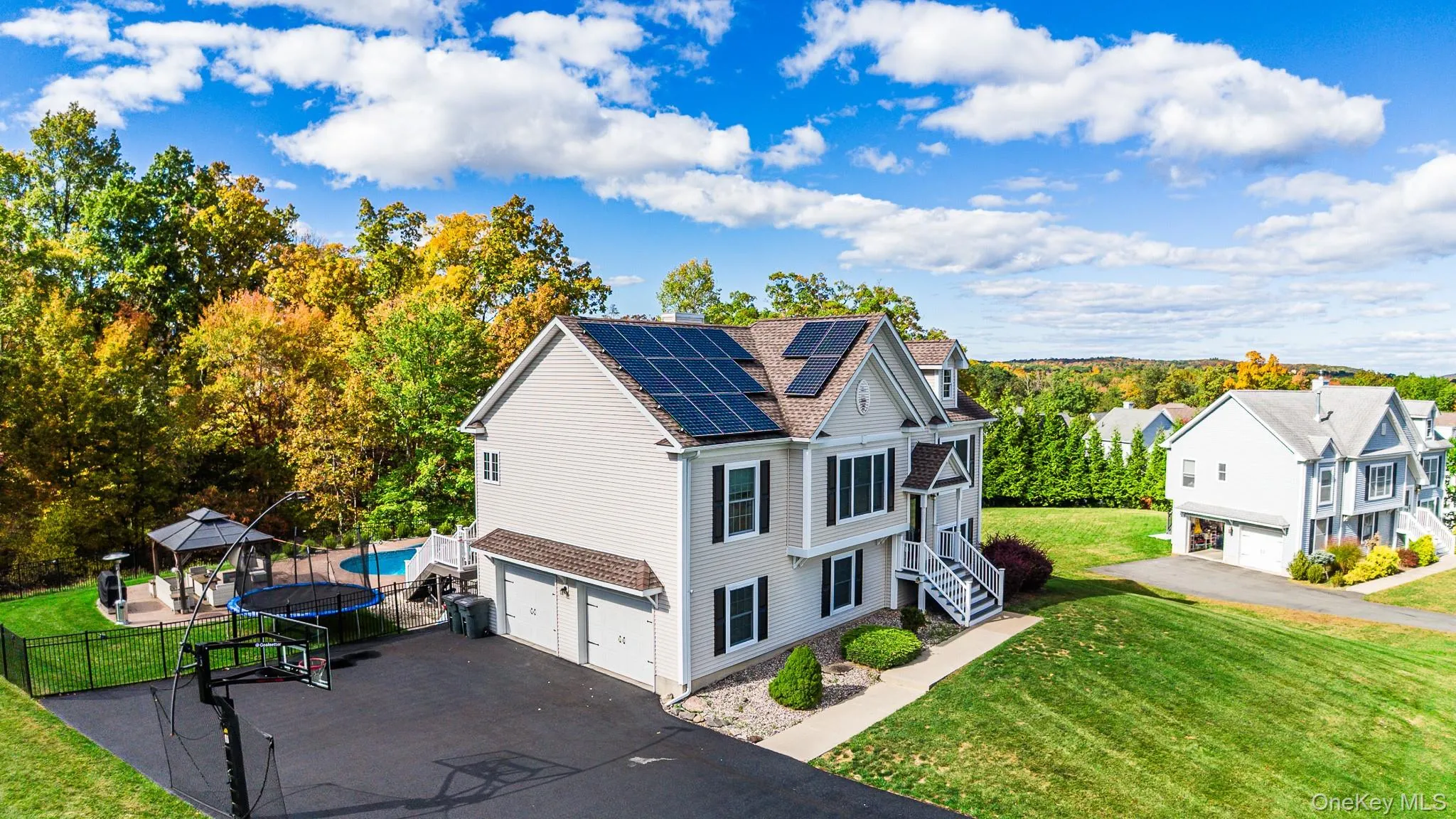 View of home's exterior with a trampoline, an attached garage, solar panels, asphalt driveway, and a shingled roof View of home's exterior with a trampoline, an attached garage, solar panels, asphalt driveway, and a shingled roof