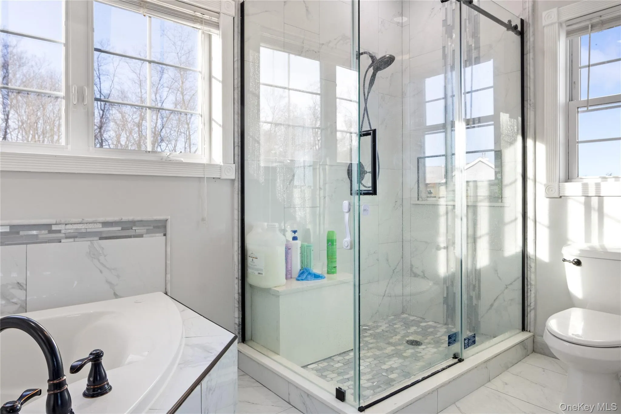 Bathroom with a garden tub, marble finish floors, and a marble finish shower Bathroom with a garden tub, marble finish floors, and a marble finish shower