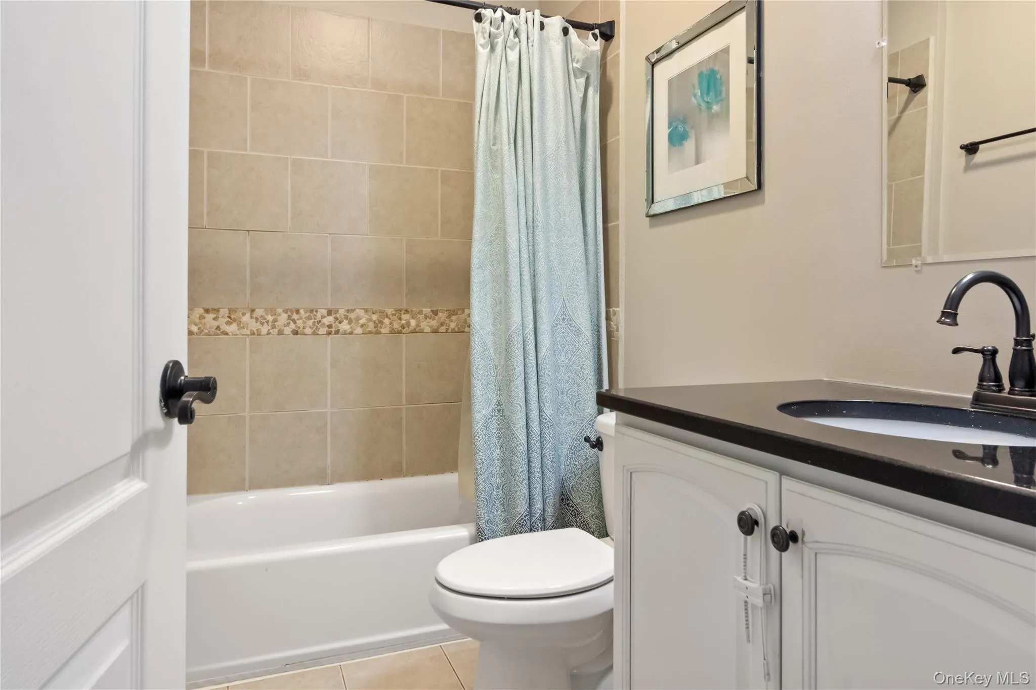 Bathroom featuring vanity, shower / bathtub combination with curtain, and light tile patterned floors Bathroom featuring vanity, shower / bathtub combination with curtain, and light tile patterned floors