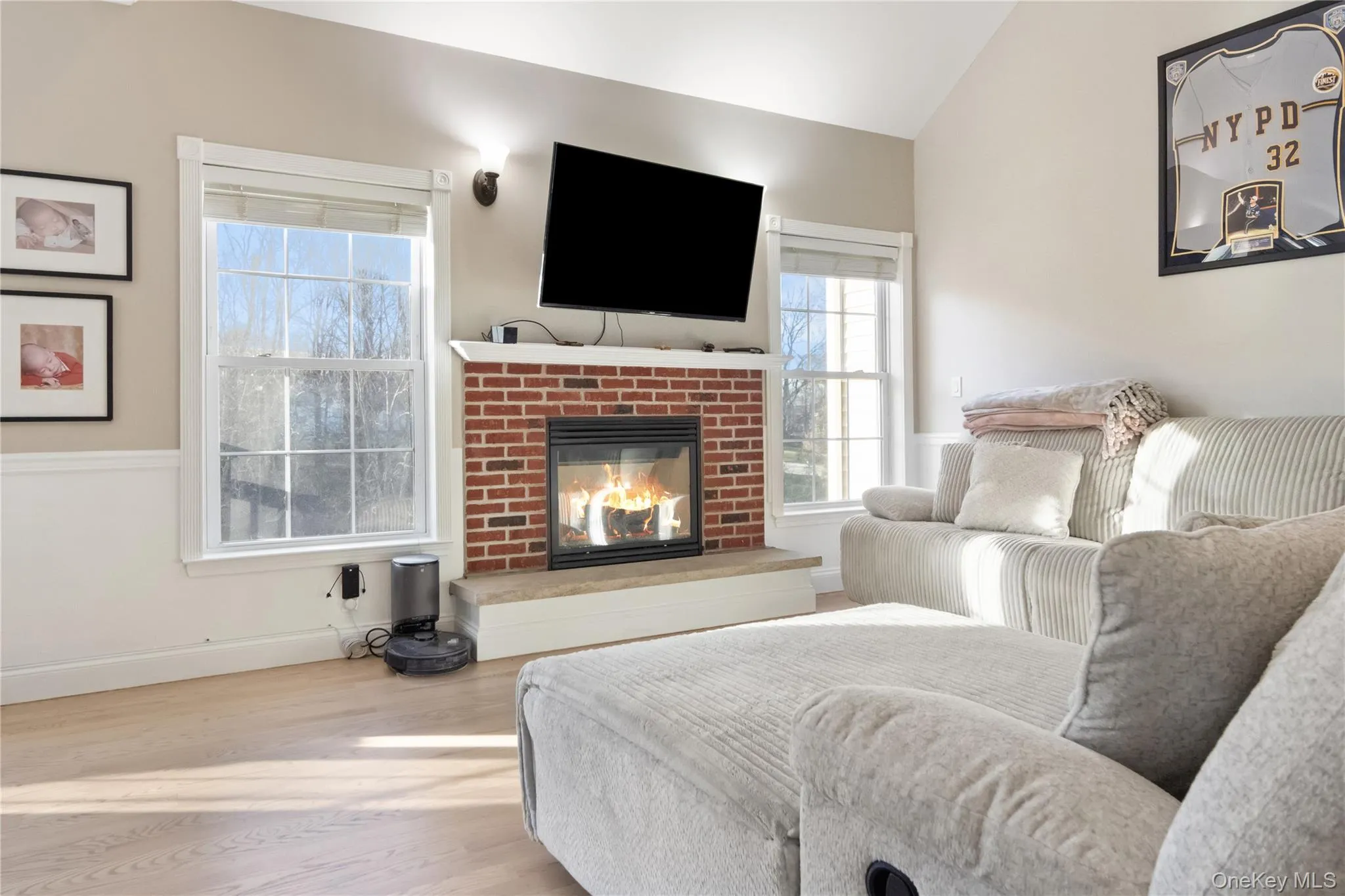 Bedroom with a brick fireplace, vaulted ceiling, and wood finished floors Bedroom with a brick fireplace, vaulted ceiling, and wood finished floors