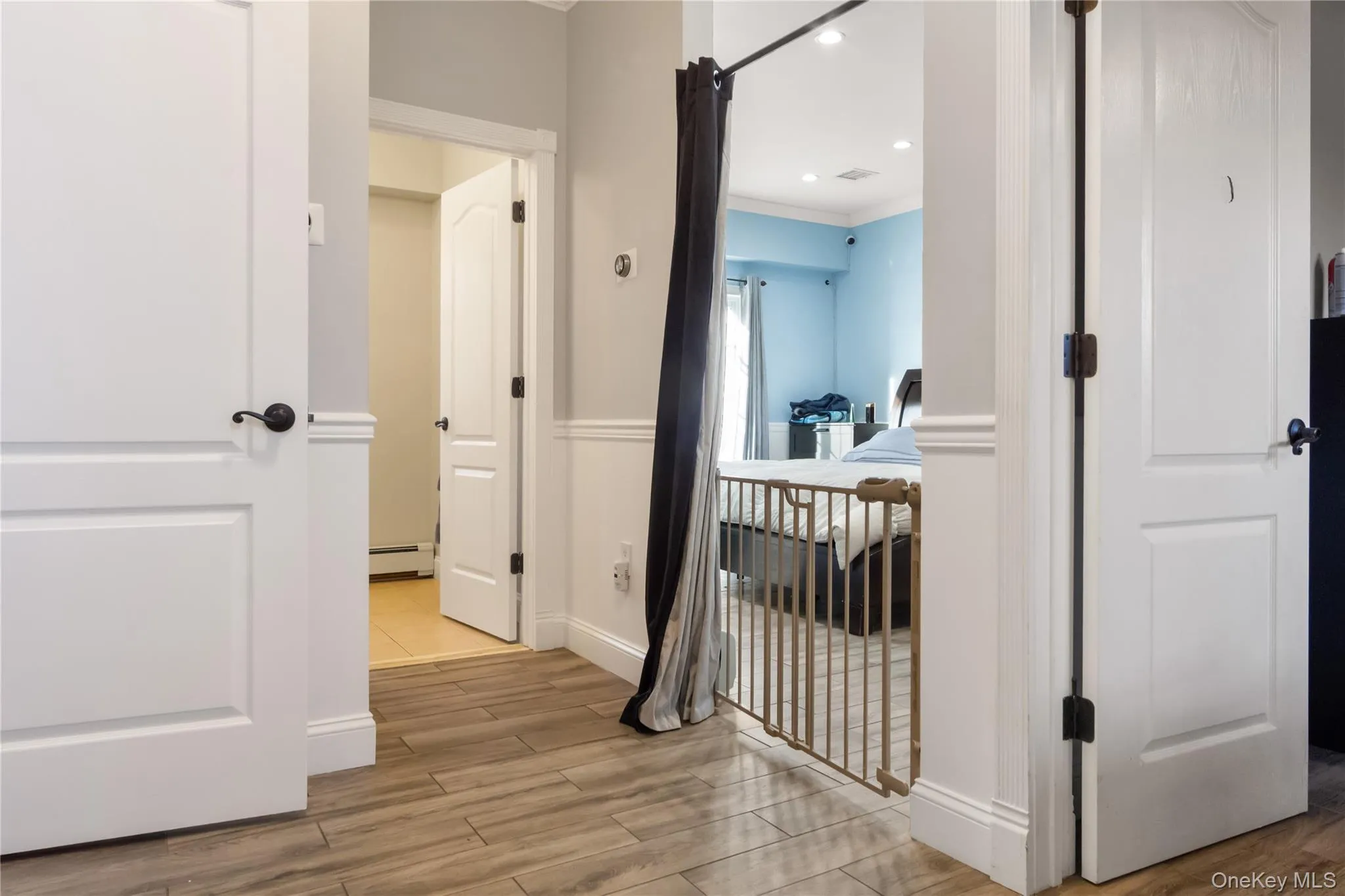 Hallway featuring wood tiled floors, crown molding, a baseboard heating unit, and recessed lighting Hallway featuring wood tiled floors, crown molding, a baseboard heating unit, and recessed lighting