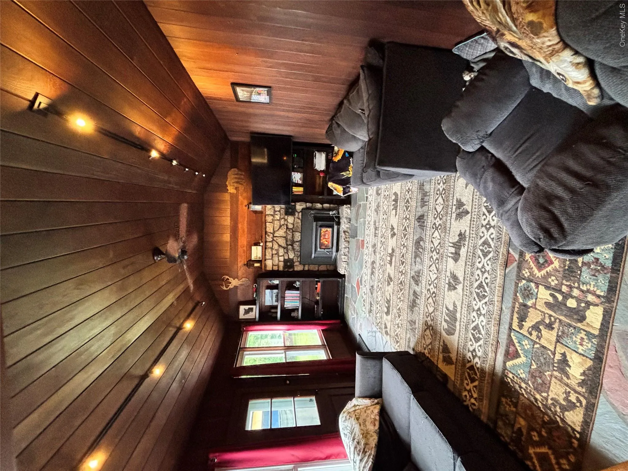 Living room with wood walls, vaulted ceiling, wood ceiling, a fireplace, and wood finished floors Living room with wood walls, vaulted ceiling, wood ceiling, a fireplace, and wood finished floors