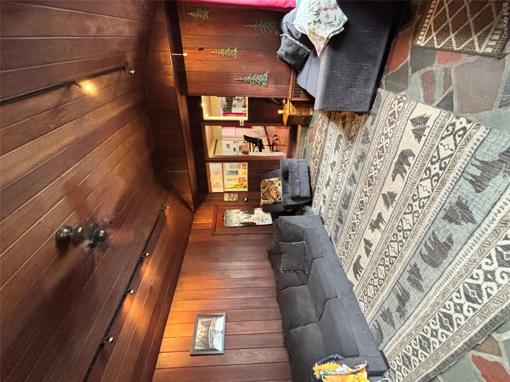 Living room featuring lofted ceiling, wooden walls, wood ceiling, and rail lighting Living room featuring lofted ceiling, wooden walls, wood ceiling, and rail lighting