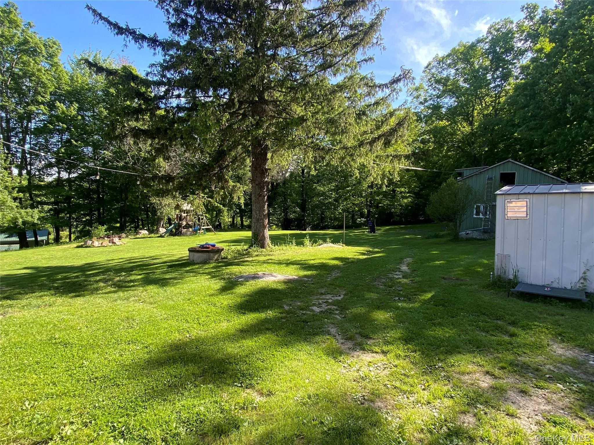View of grassy yard featuring a playground and view of scattered trees View of grassy yard featuring a playground and view of scattered trees