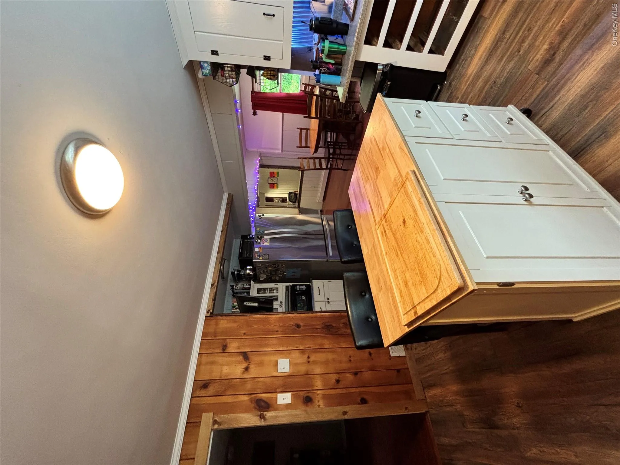 Kitchen featuring wood counters, dark wood-type flooring, freestanding refrigerator, white cabinetry, and ornamental molding Kitchen featuring wood counters, dark wood-type flooring, freestanding refrigerator, white cabinetry, and ornamental molding