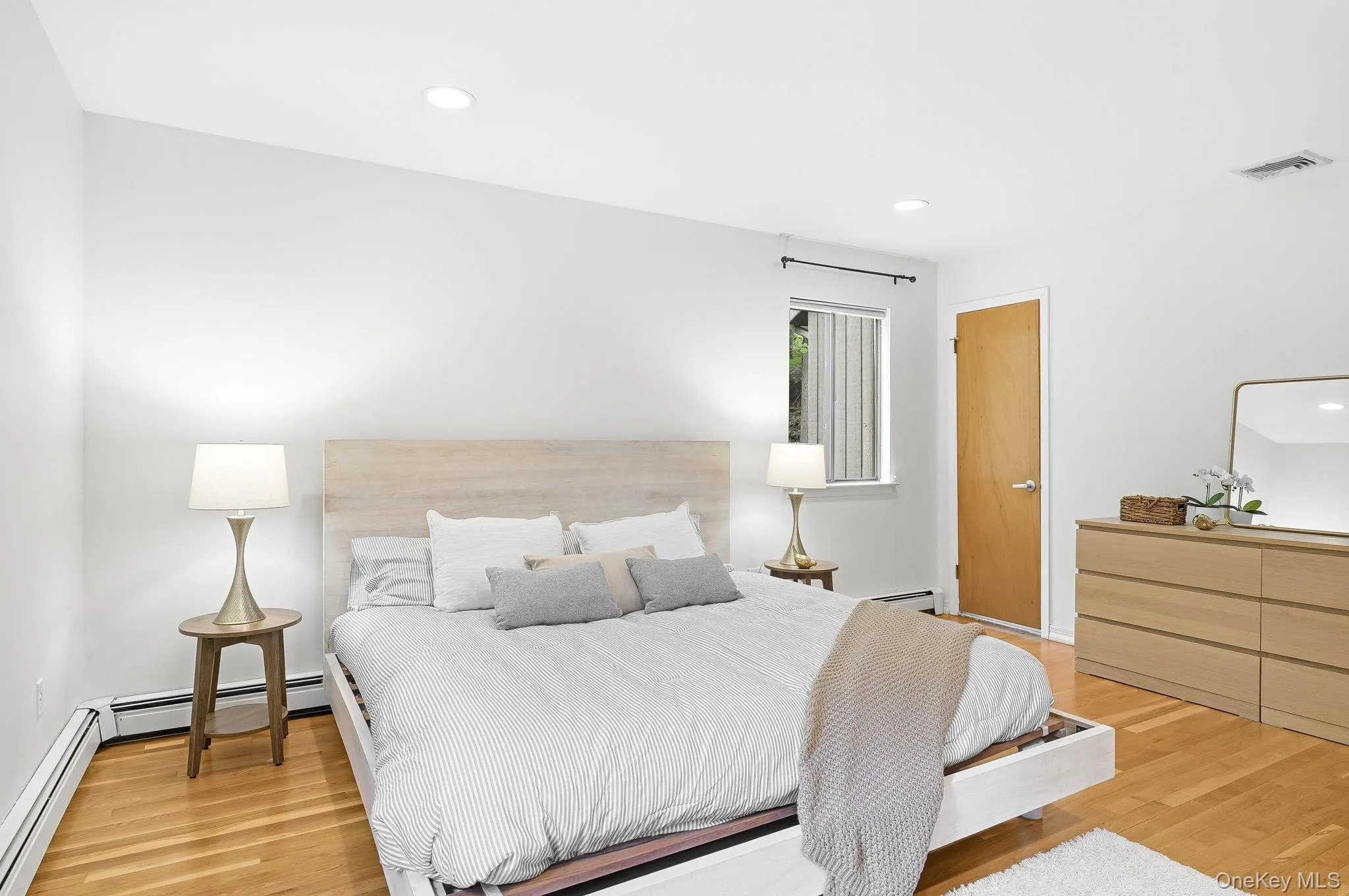 Large primary bedroom on the ground floor featurning hardwood flooring throughout, recessed lighting, and an en-suite bathroom Large primary bedroom on the ground floor featurning hardwood flooring throughout, recessed lighting, and an en-suite bathroom