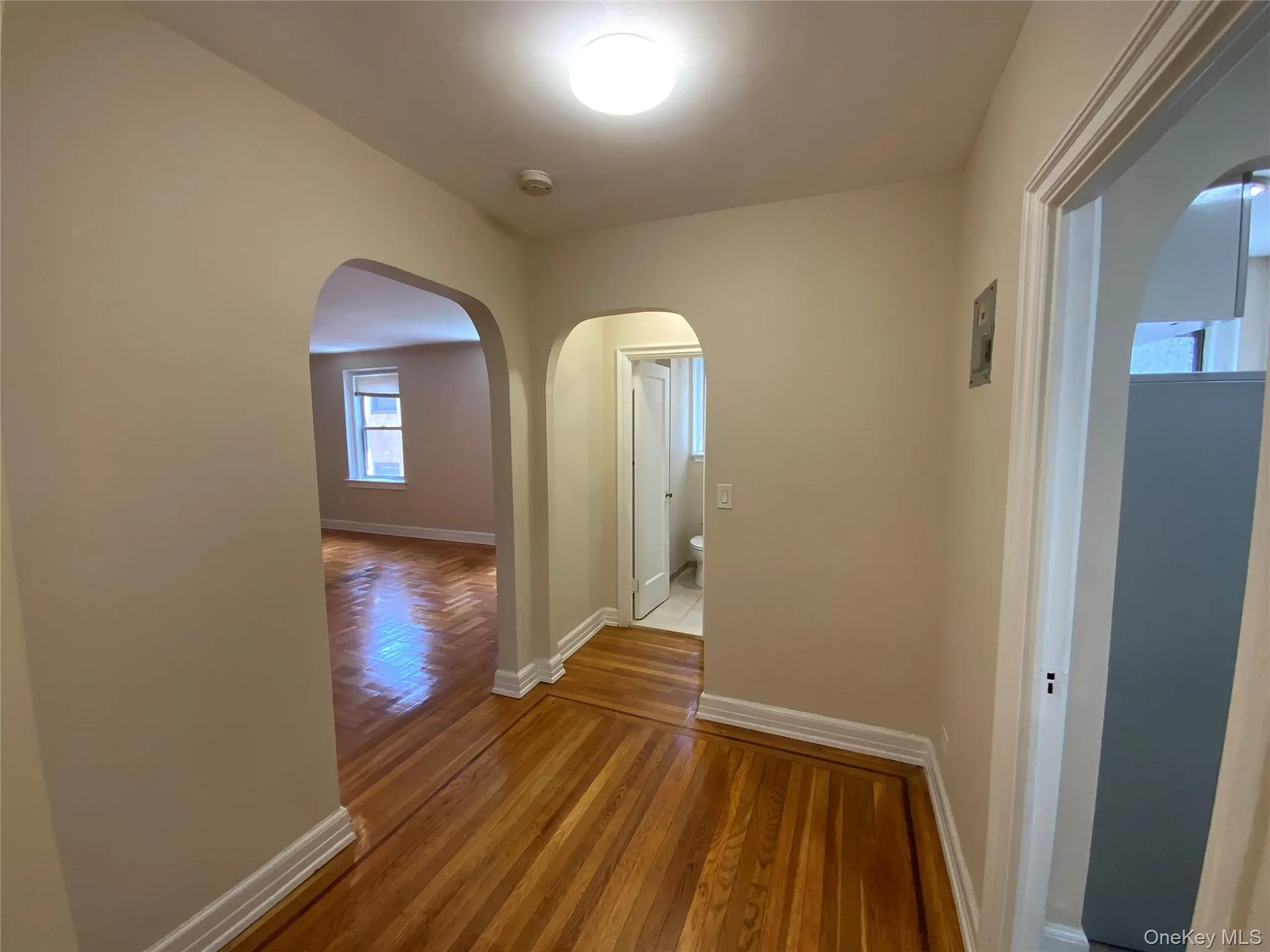 Hallway featuring wood finished floors, baseboards, and arched walkways Hallway featuring wood finished floors, baseboards, and arched walkways