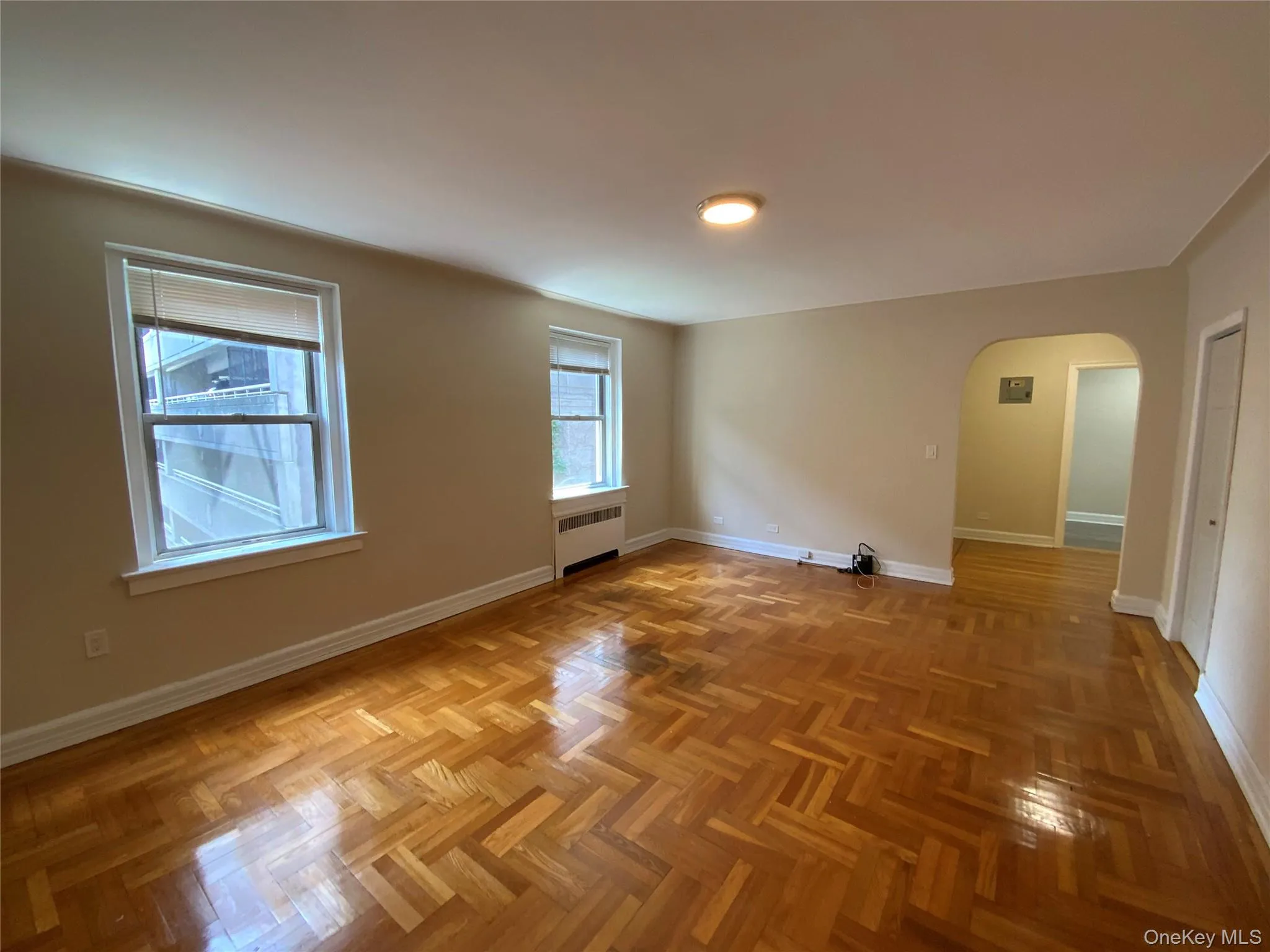 Unfurnished room featuring baseboards, arched walkways, and radiator Unfurnished room featuring baseboards, arched walkways, and radiator