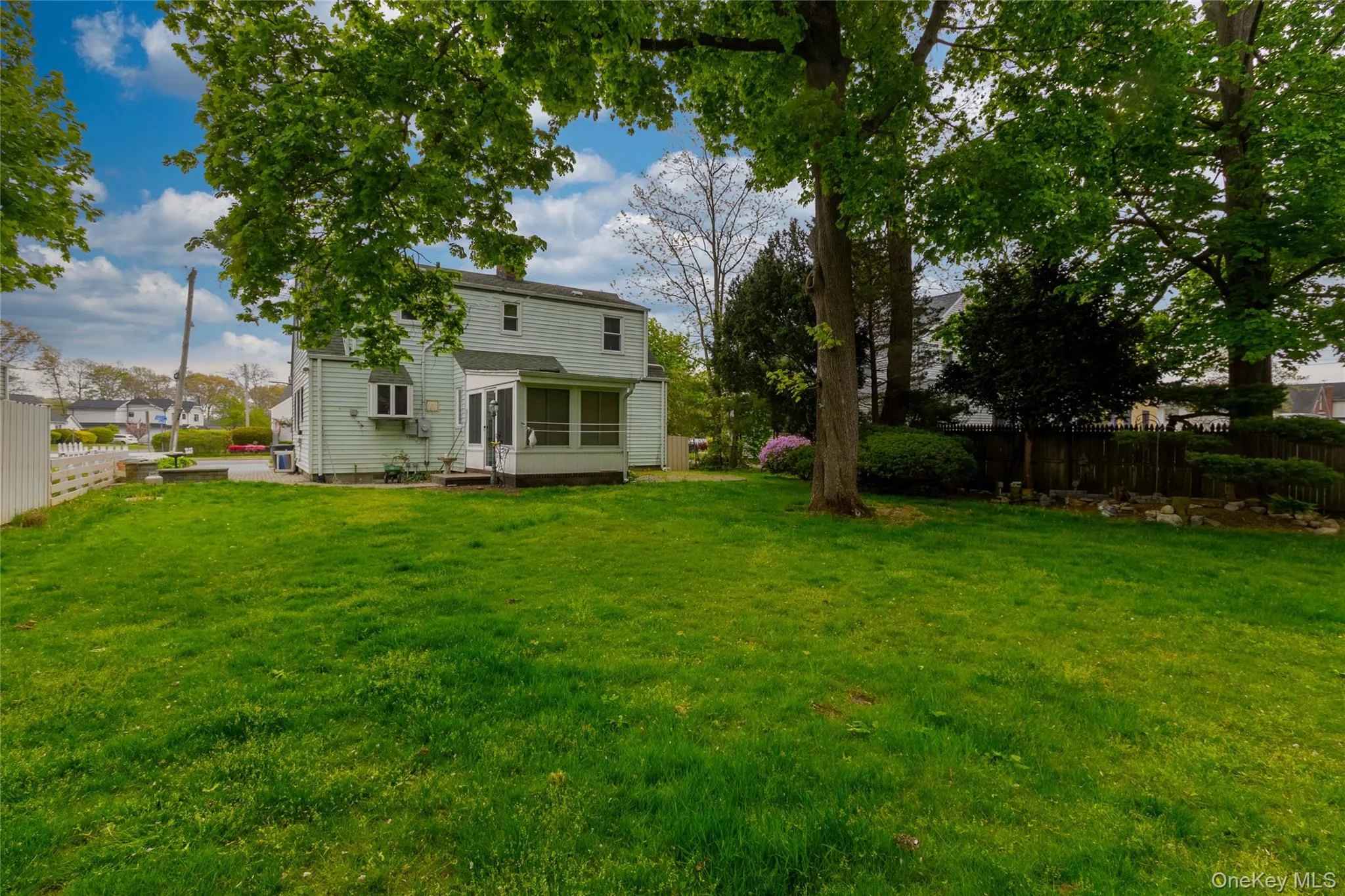 Expansive rear lawn featuring mature trees and a screened-in porch with a panel door Expansive rear lawn featuring mature trees and a screened-in porch with a panel door