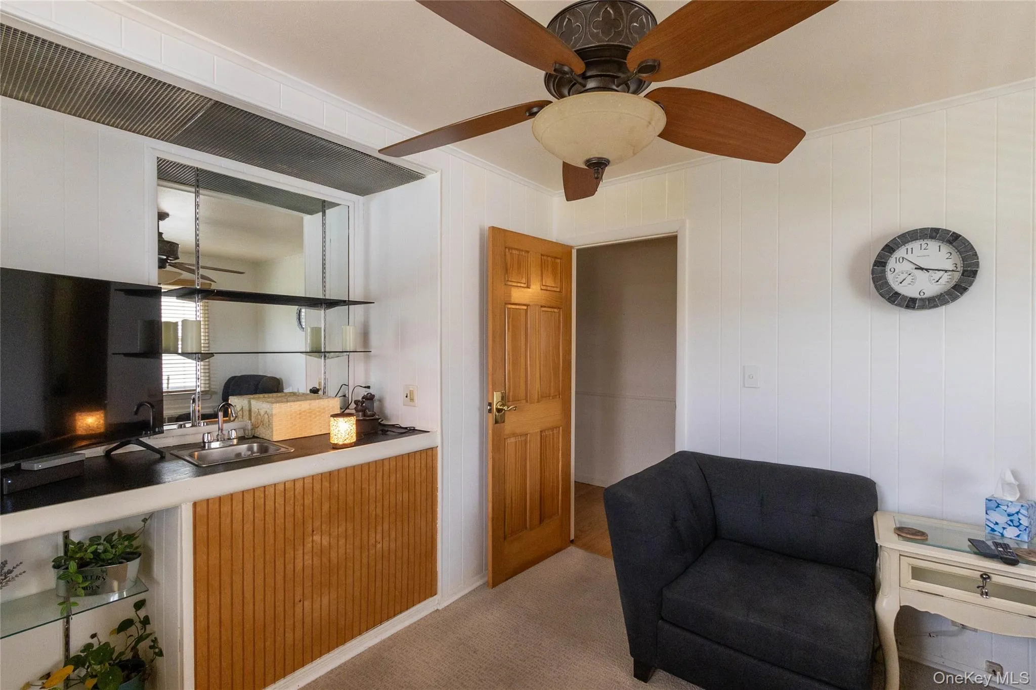 Integrated wet bar featuring a stainless steel sink, black countertop, mirrored backsplash, and glass shelving Integrated wet bar featuring a stainless steel sink, black countertop, mirrored backsplash, and glass shelving