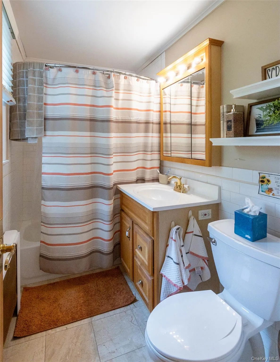 Bathroom featuring a single vanity with wood cabinetry, a white countertop, and a brass-finish faucet Bathroom featuring a single vanity with wood cabinetry, a white countertop, and a brass-finish faucet