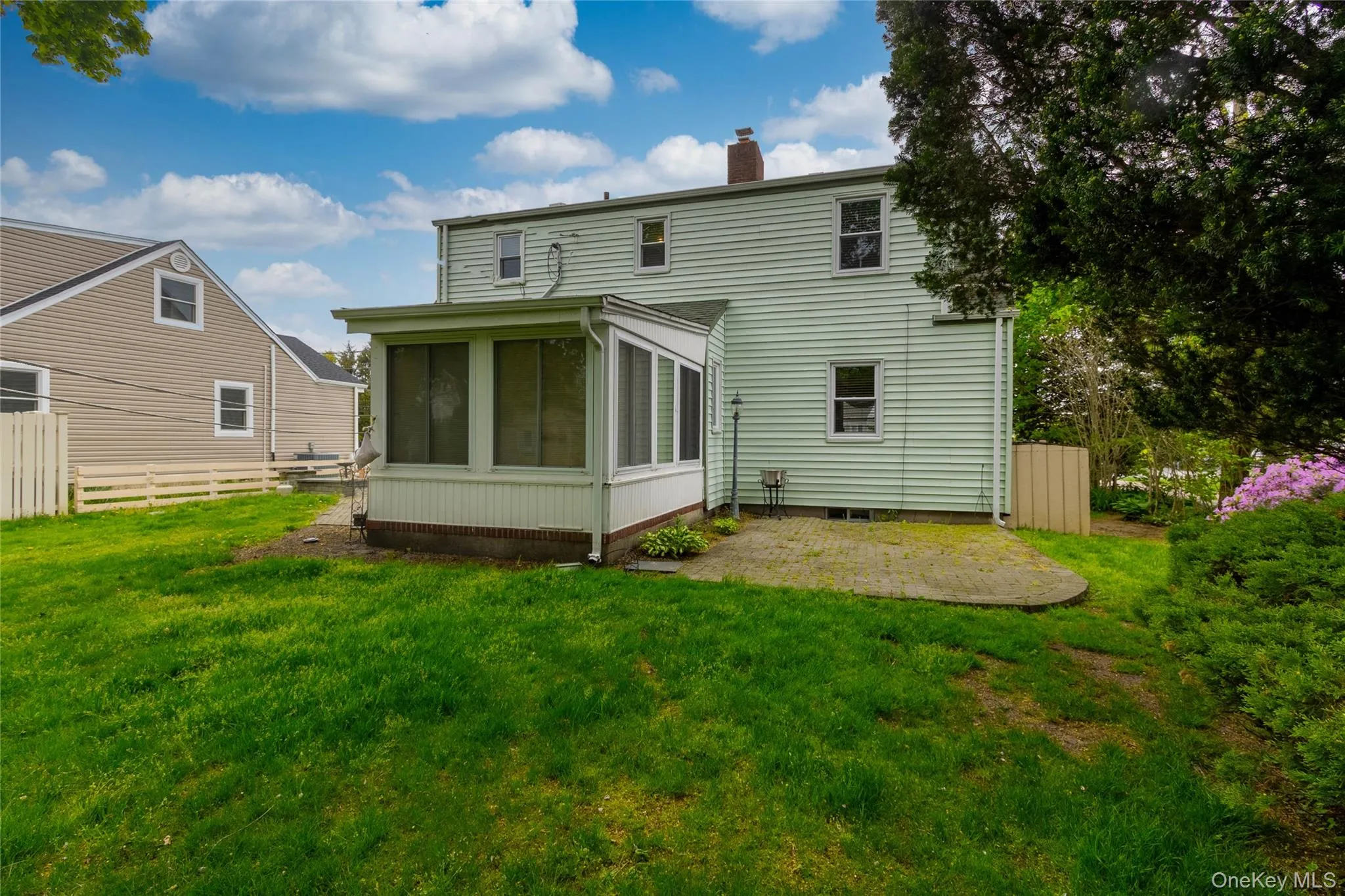 Rear exterior featuring light green siding, a screened-in porch with white trim, and a concrete patio Rear exterior featuring light green siding, a screened-in porch with white trim, and a concrete patio