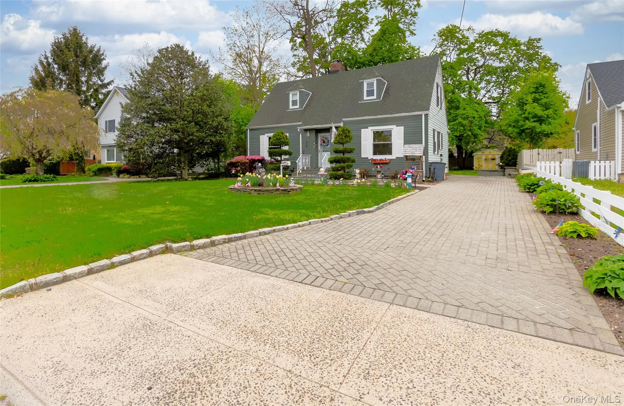 Cape Cod style home featuring a gabled roof, dormer windows, and white window shutters Cape Cod style home featuring a gabled roof, dormer windows, and white window shutters