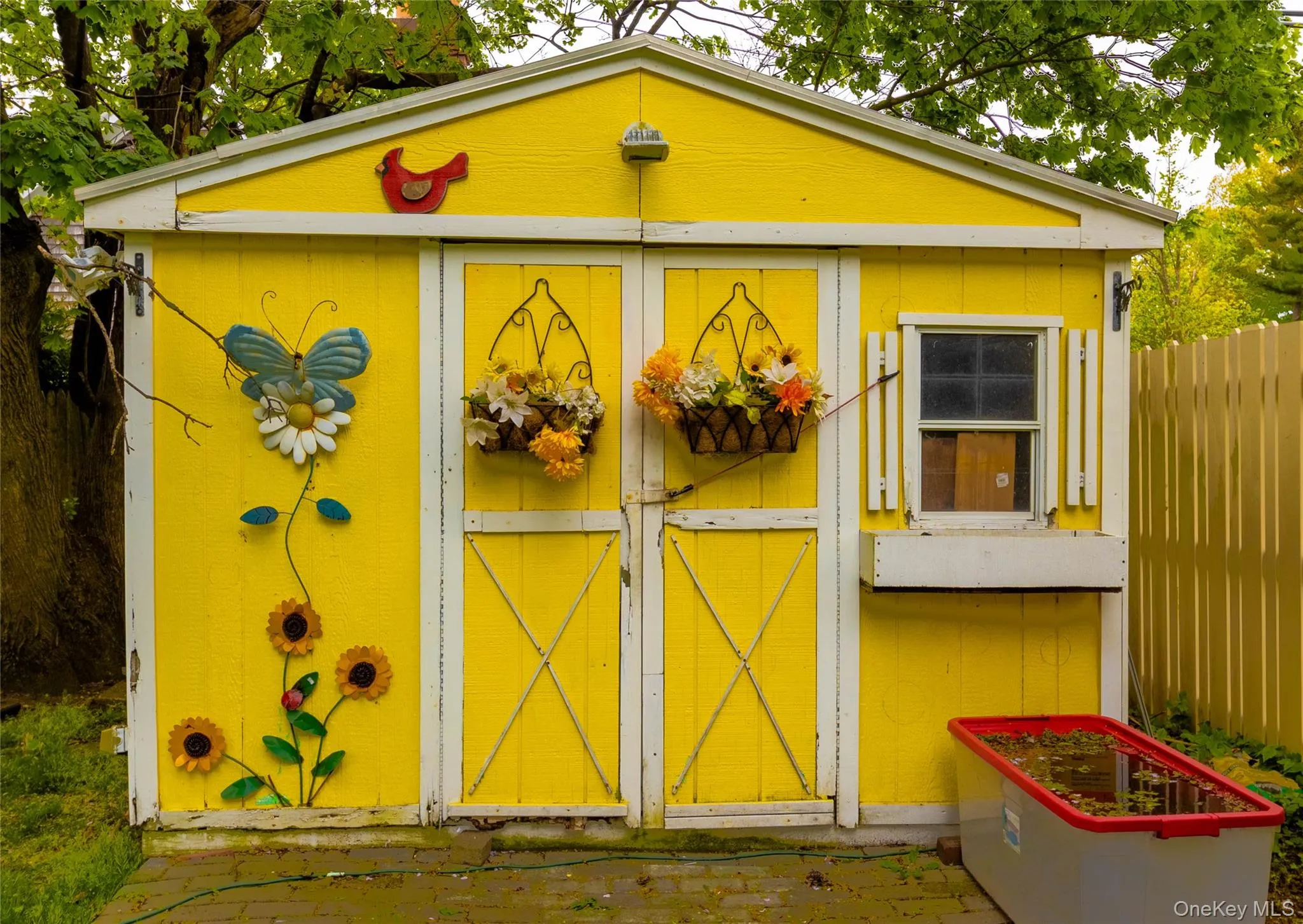 Bright yellow exterior shed with white trim, double entry doors, a side window with shutters, and an integrated window box Bright yellow exterior shed with white trim, double entry doors, a side window with shutters, and an integrated window box