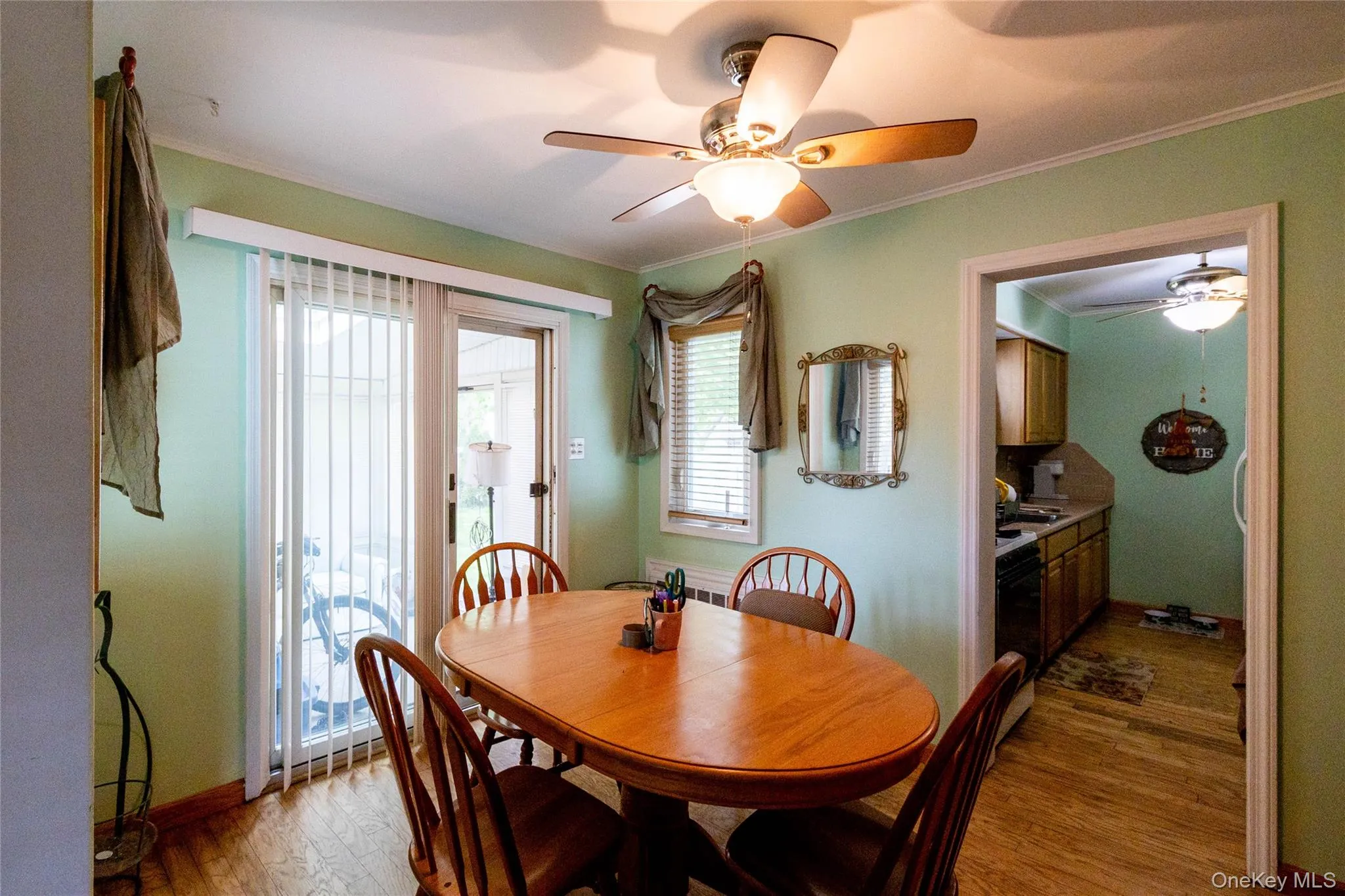 Dining area featuring wood-finish flooring, a ceiling fan with integrated lighting, and direct patio access through sliding glass doors Dining area featuring wood-finish flooring, a ceiling fan with integrated lighting, and direct patio access through sliding glass doors