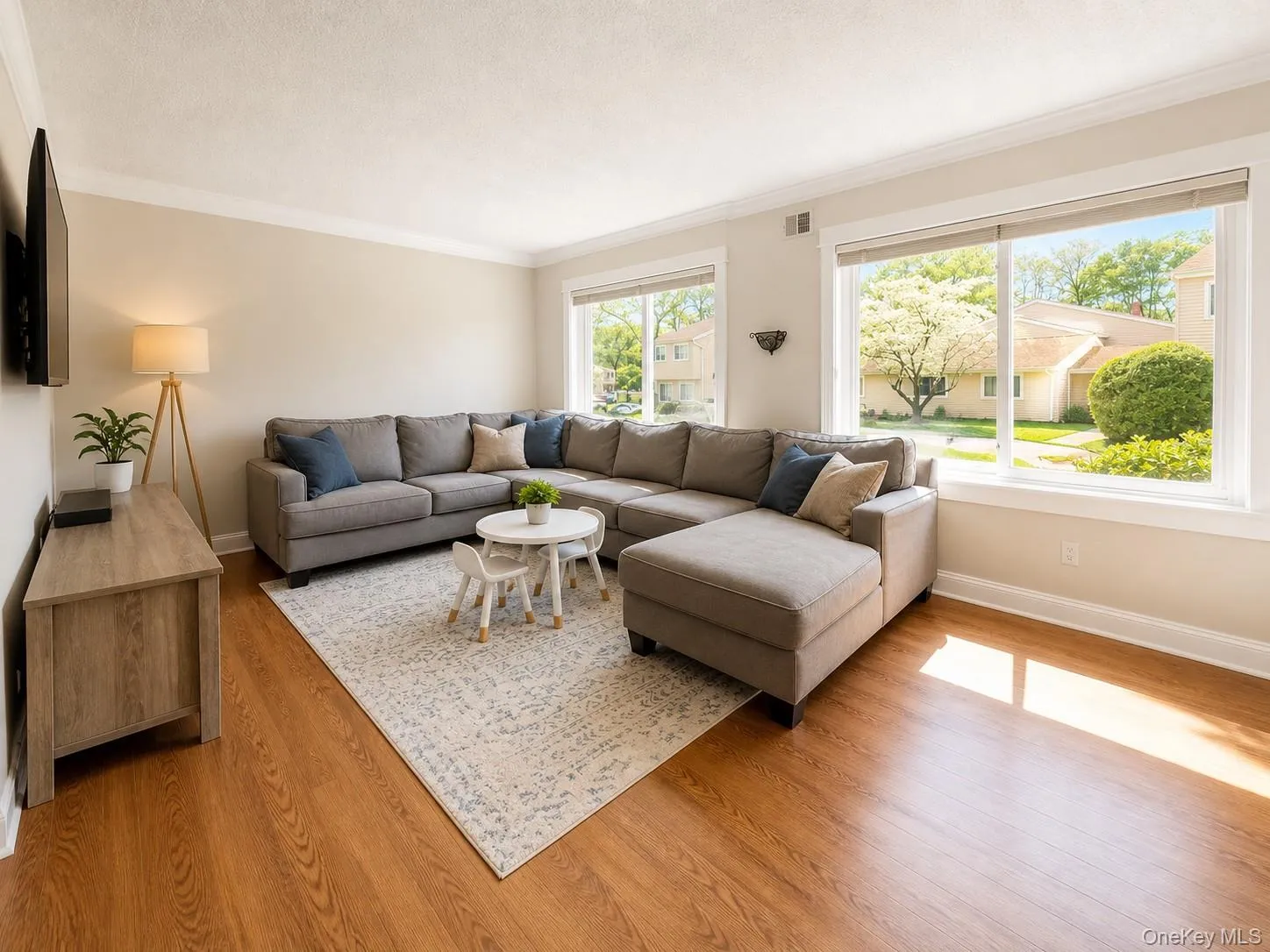 Spacious living area featuring expansive windows, wood-finish flooring, and crown molding Spacious living area featuring expansive windows, wood-finish flooring, and crown molding