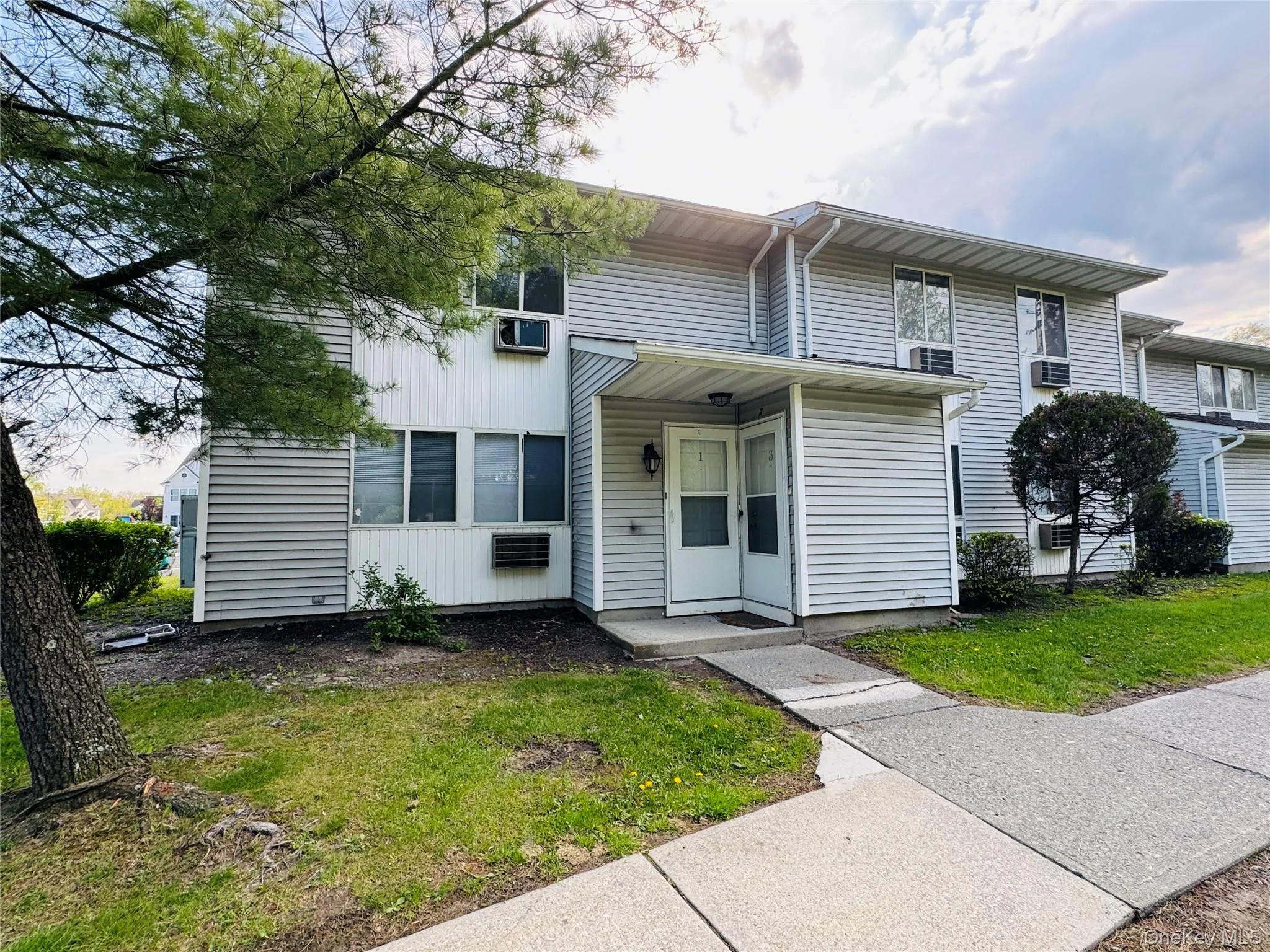 Entry way of Condo with Gray horizontal vinyl siding exterior with a covered entry, multiple windows, and partial mature tree coverage. Entry way of Condo with Gray horizontal vinyl siding exterior with a covered entry, multiple windows, and partial mature tree coverage.