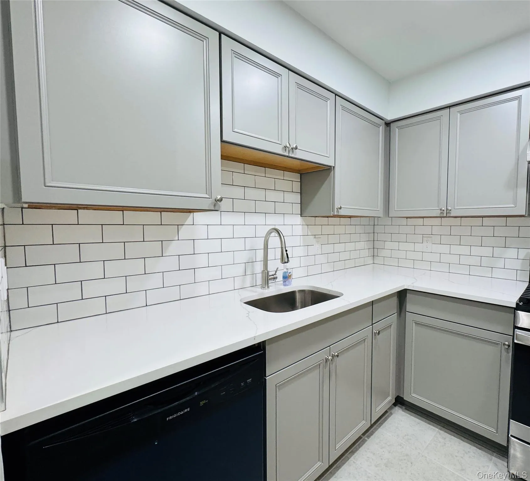 Kitchen featuring light gray cabinetry, white subway tile backsplash, white quartz countertops. Kitchen featuring light gray cabinetry, white subway tile backsplash, white quartz countertops.