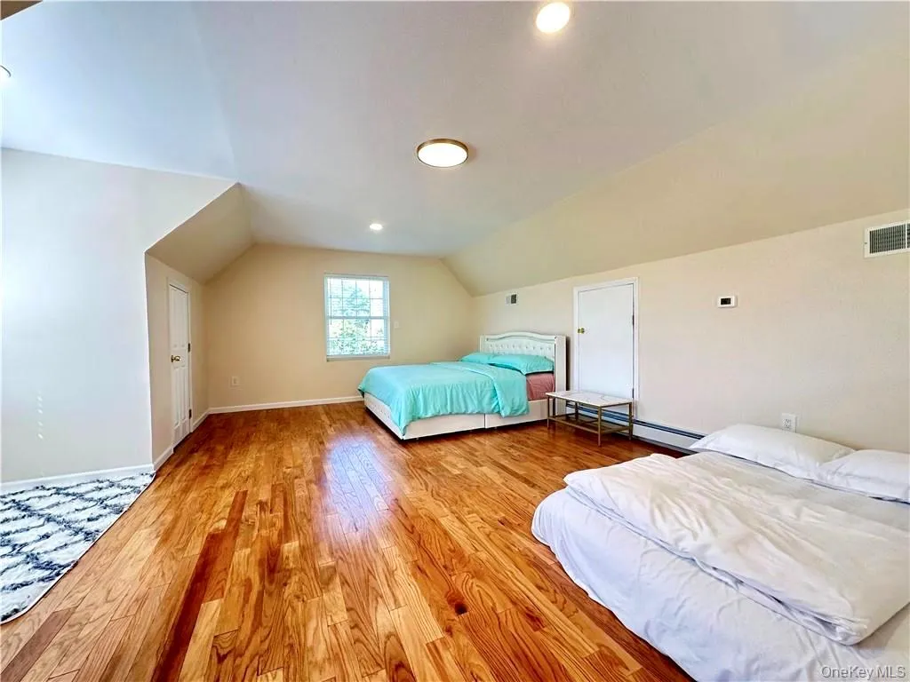 Bedroom featuring vaulted ceiling, light wood finished floors, recessed lighting, and baseboard heating Bedroom featuring vaulted ceiling, light wood finished floors, recessed lighting, and baseboard heating