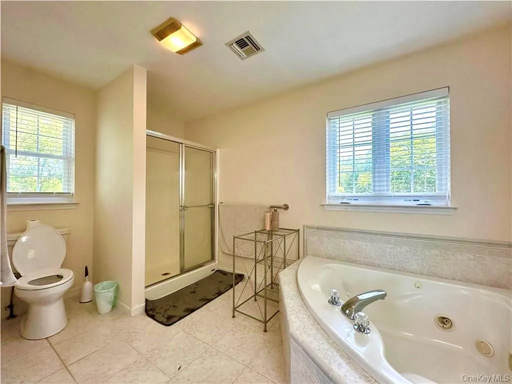 Full bathroom with a tub with jets, a stall shower, and light tile patterned floors Full bathroom with a tub with jets, a stall shower, and light tile patterned floors