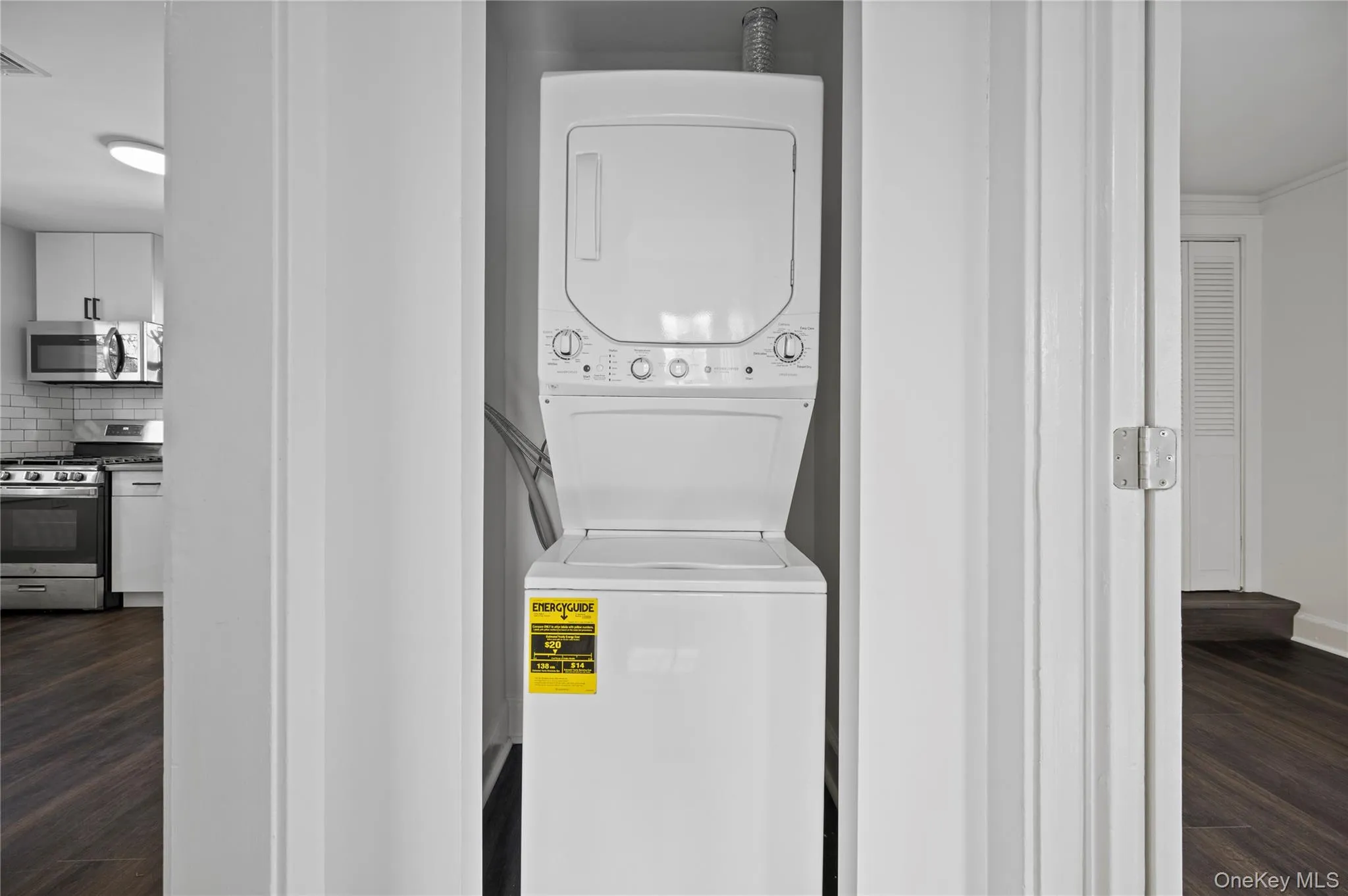 Laundry room featuring dark wood-style floors and stacked washer and clothes dryer Laundry room featuring dark wood-style floors and stacked washer and clothes dryer