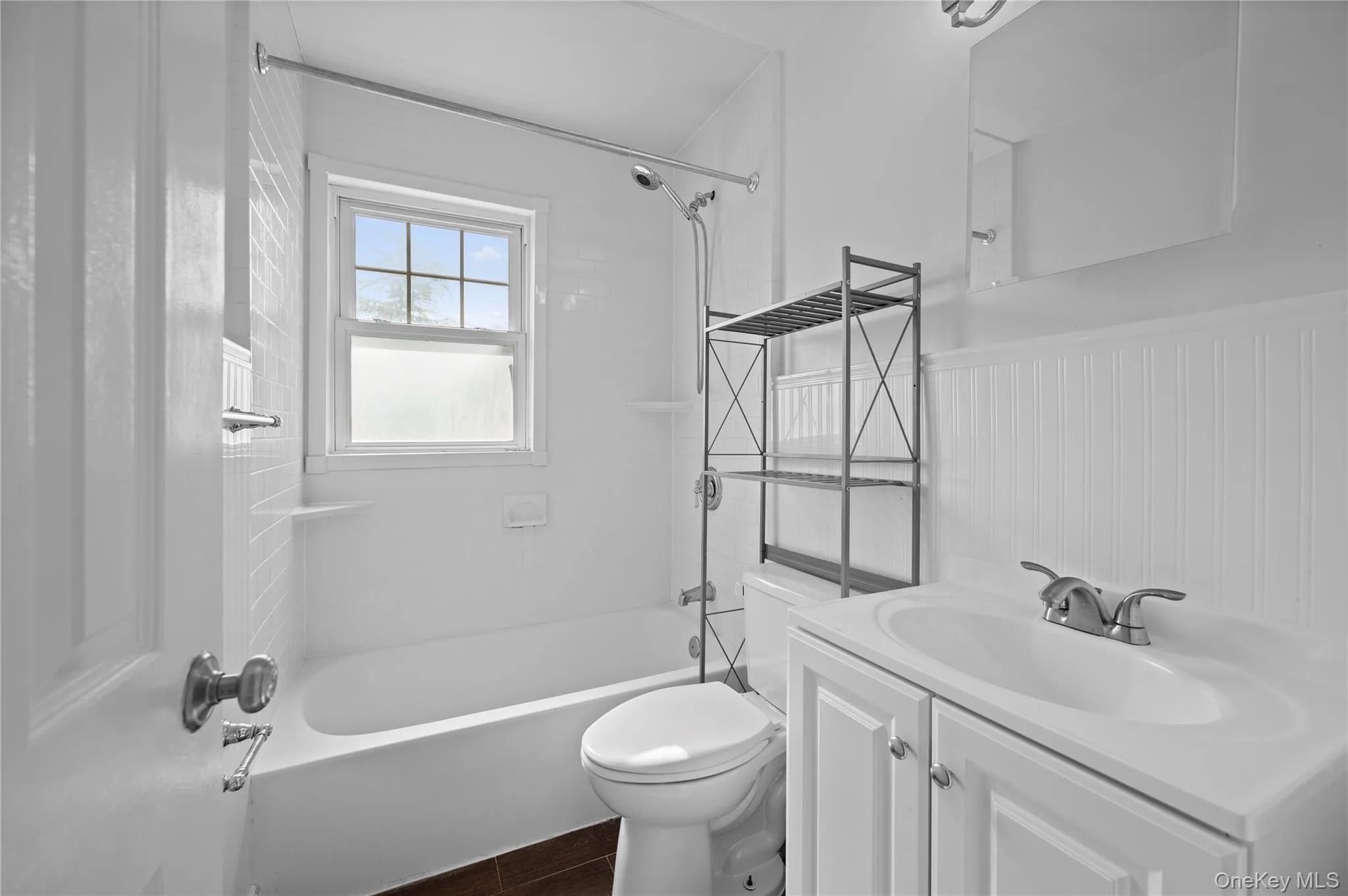 Full bathroom featuring shower / washtub combination, vanity, and a wainscoted wall Full bathroom featuring shower / washtub combination, vanity, and a wainscoted wall