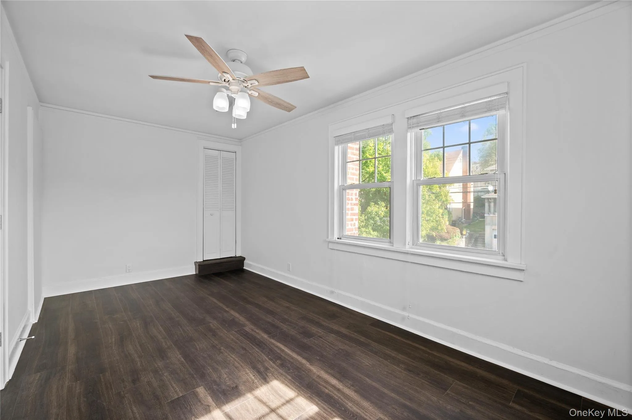 Empty room with crown molding, dark wood finished floors, and ceiling fan Empty room with crown molding, dark wood finished floors, and ceiling fan