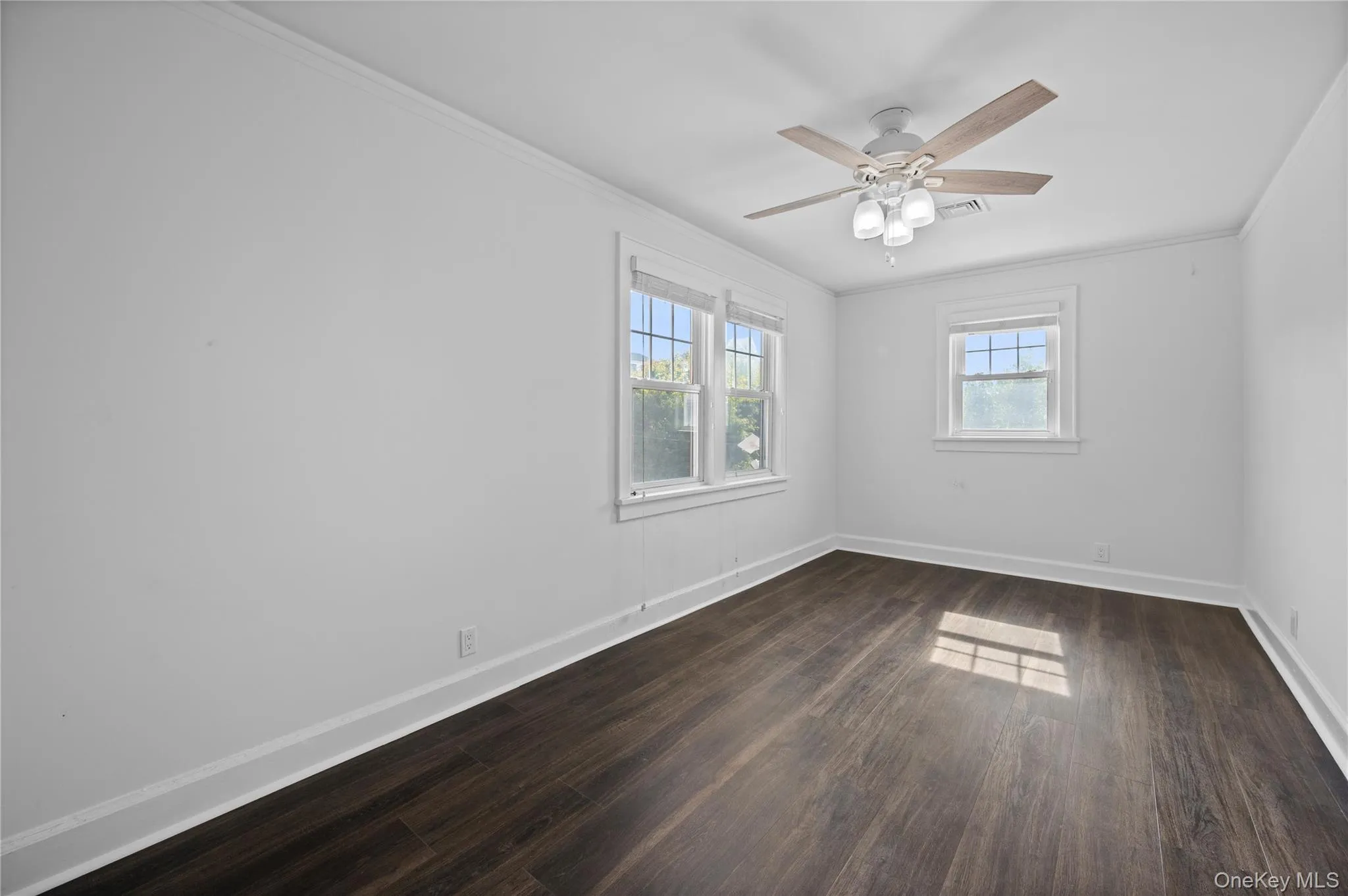 Spare room featuring crown molding, dark wood finished floors, and ceiling fan Spare room featuring crown molding, dark wood finished floors, and ceiling fan