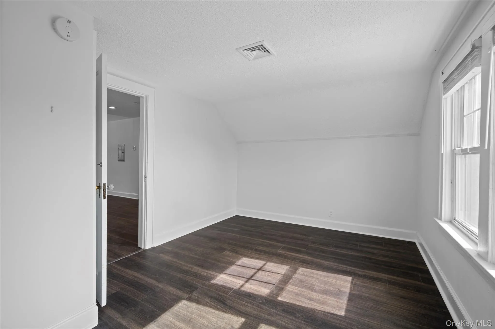 Additional living space with vaulted ceiling, dark wood finished floors, and a textured ceiling Additional living space with vaulted ceiling, dark wood finished floors, and a textured ceiling