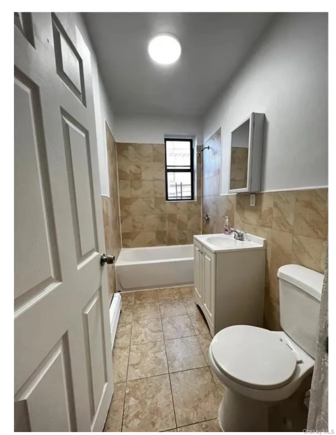 Full bath featuring vanity, toilet, shower / bathtub combination, and tile walls Full bath featuring vanity, toilet, shower / bathtub combination, and tile walls
