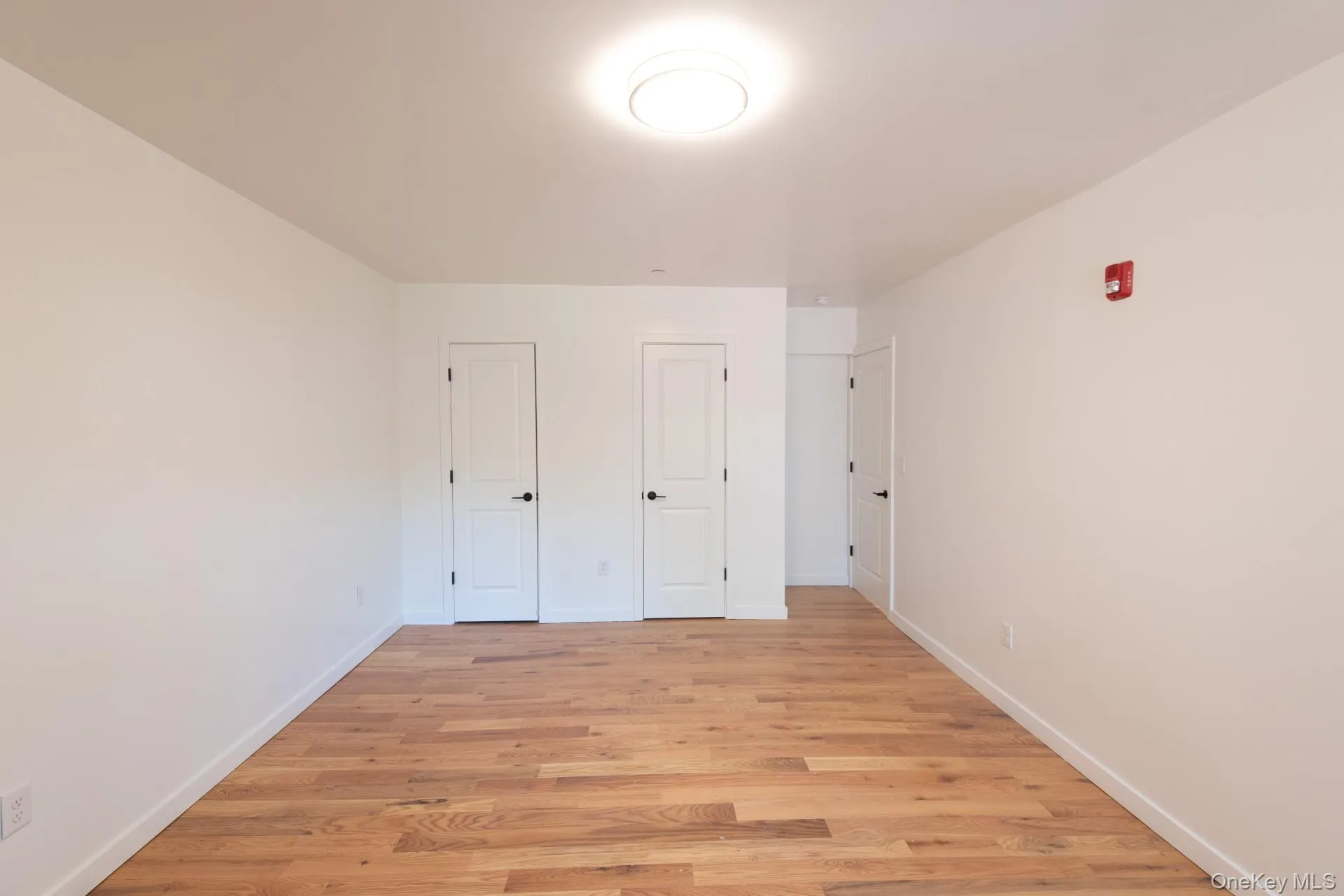 Primary bedroom with new hardwood floors and lighting; two closets Primary bedroom with new hardwood floors and lighting; two closets
