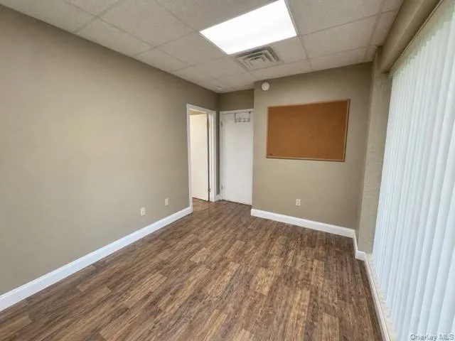 Interior room featuring wood-finish flooring, neutral wall paint, and white baseboards Interior room featuring wood-finish flooring, neutral wall paint, and white baseboards