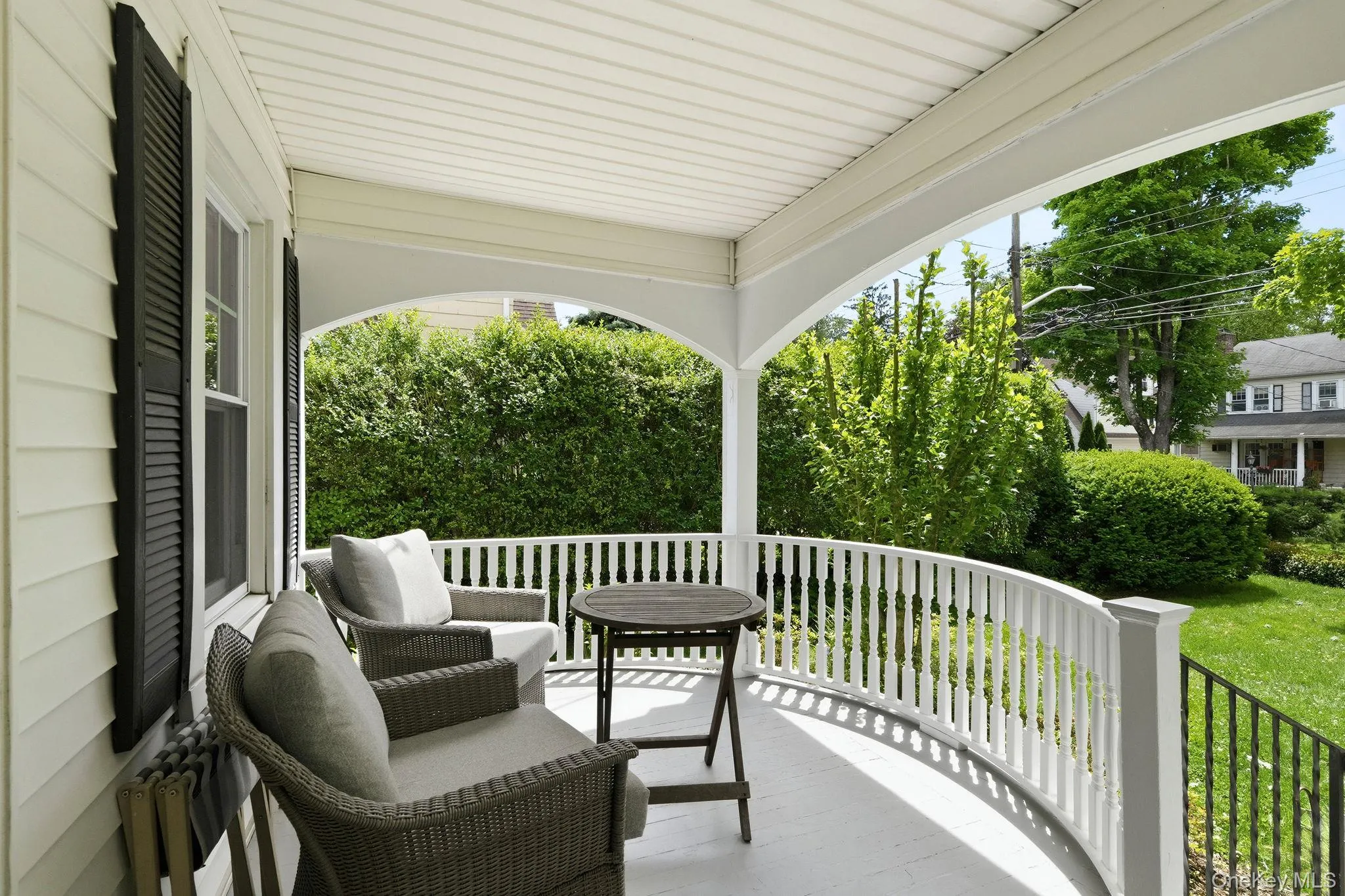 A standout architectural feature, the covered front porch showcases beautiful curved railings and tranquil views of the meticulously maintained grounds. A standout architectural feature, the covered front porch showcases beautiful curved railings and tranquil views of the meticulously maintained grounds.