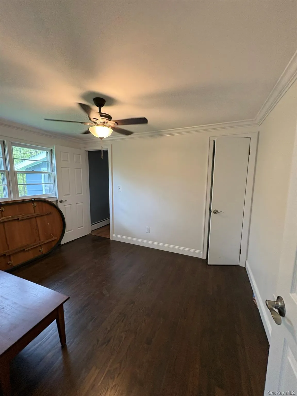 Room featuring rich wood-finish flooring, white painted walls, and extensive crown molding Room featuring rich wood-finish flooring, white painted walls, and extensive crown molding