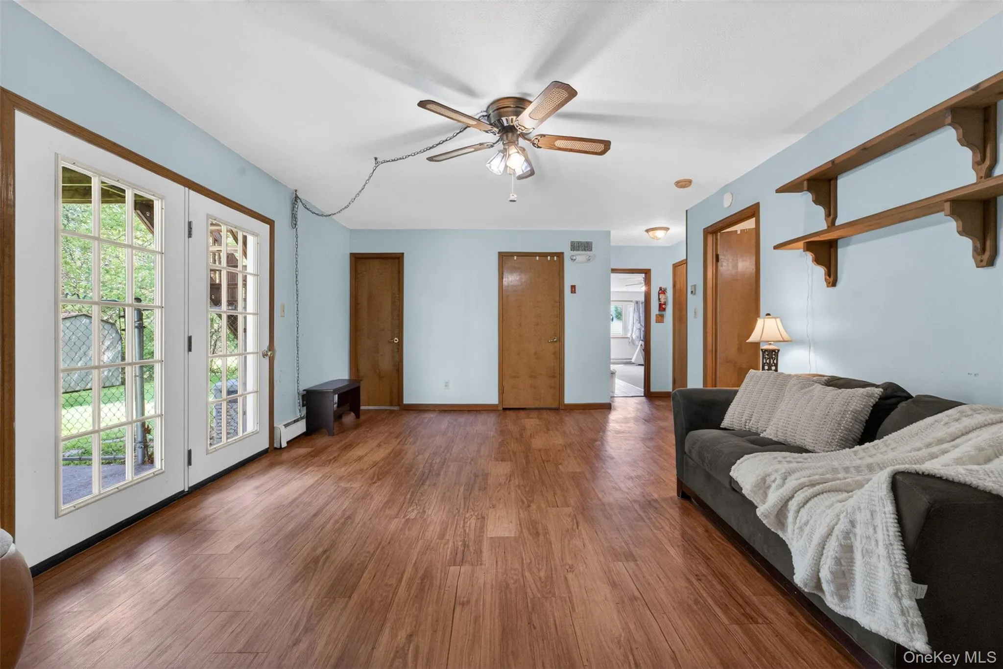 Spacious room featuring wood-finish flooring, light blue walls, and white trim Spacious room featuring wood-finish flooring, light blue walls, and white trim