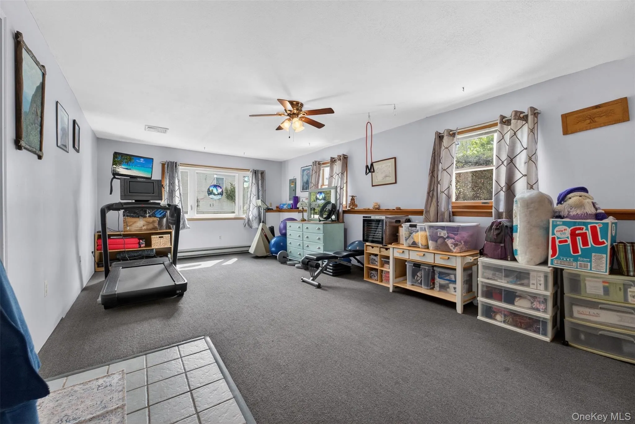 Spacious room featuring light blue walls, gray carpet, and multiple windows allowing natural illumination Spacious room featuring light blue walls, gray carpet, and multiple windows allowing natural illumination
