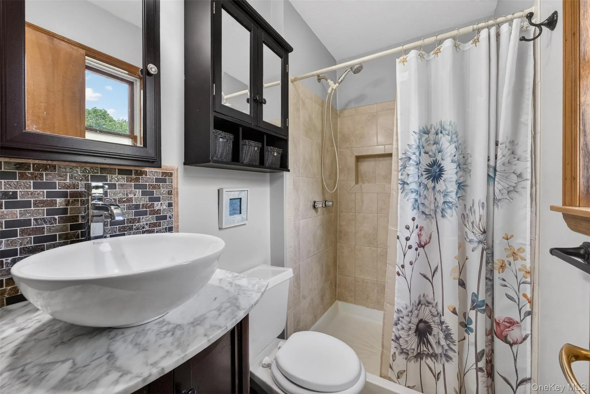 Bathroom featuring a vessel sink on a stone-finish countertop, mosaic tile backsplash, and a dark wood-finish vanity with a matching framed mirror, Medicine Cabinet, and Stand up Shower Bathroom featuring a vessel sink on a stone-finish countertop, mosaic tile backsplash, and a dark wood-finish vanity with a matching framed mirror, Medicine Cabinet, and Stand up Shower