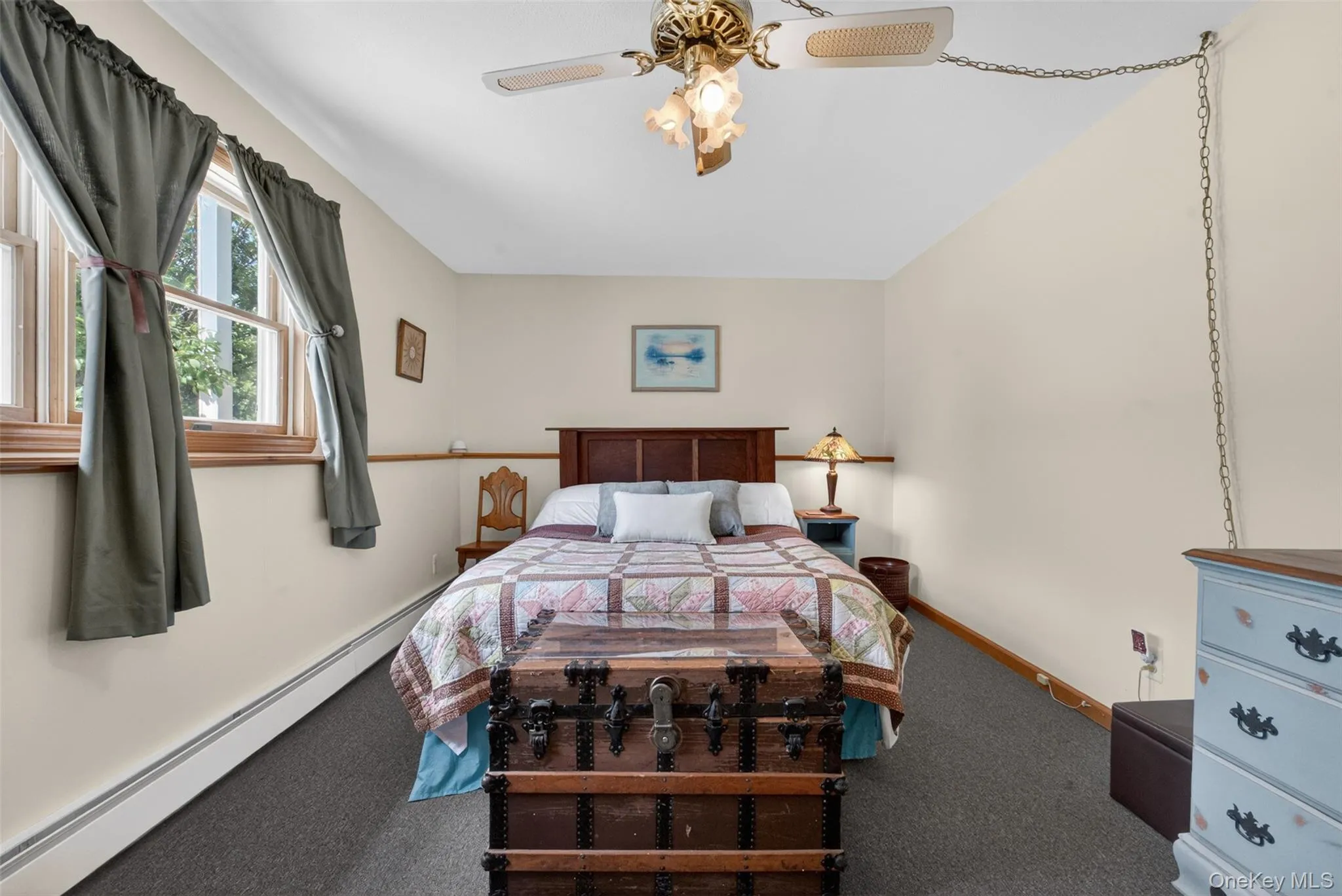 Bedroom featuring neutral wall paint, carpet flooring, a ceiling fan with light fixture, and two double-hung windows with trim Bedroom featuring neutral wall paint, carpet flooring, a ceiling fan with light fixture, and two double-hung windows with trim