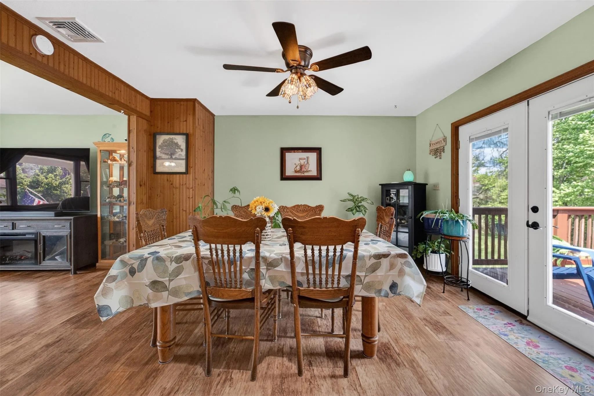 Dining area featuring wood-finish flooring, light green walls, and a ceiling fan with light fixture Dining area featuring wood-finish flooring, light green walls, and a ceiling fan with light fixture