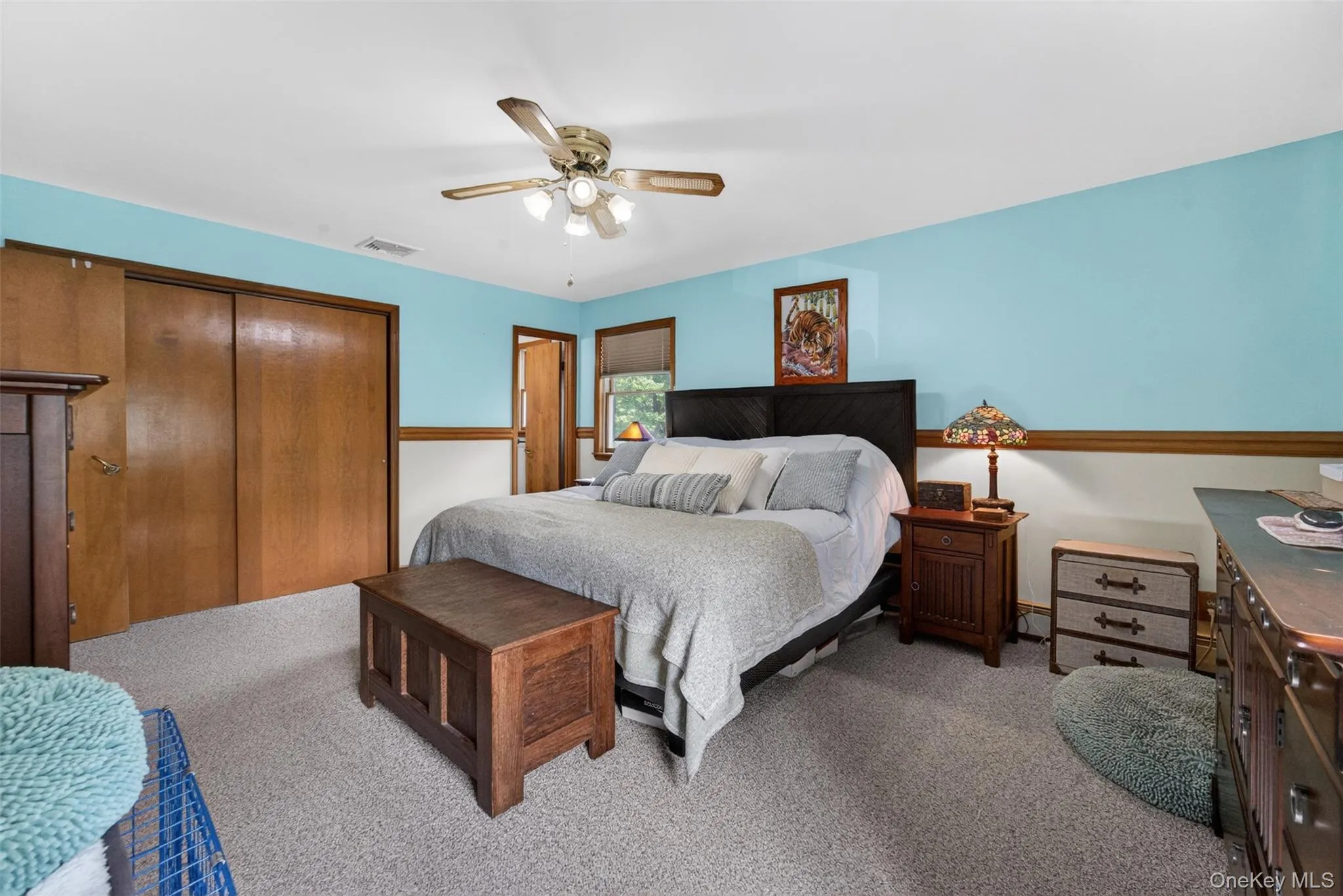 Bedroom featuring light-toned carpeting, a ceiling fan with integrated lighting, and a window with wood trim Bedroom featuring light-toned carpeting, a ceiling fan with integrated lighting, and a window with wood trim
