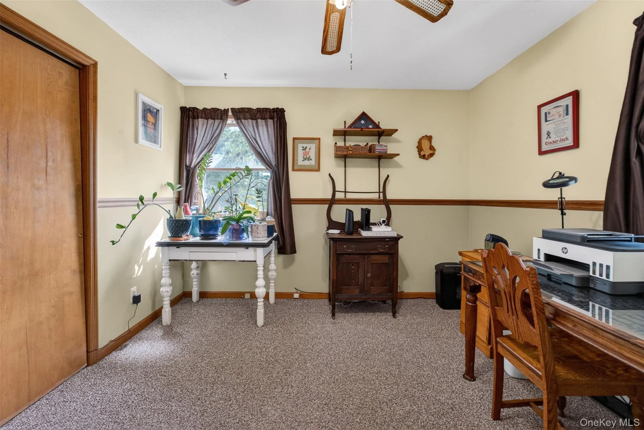 Carpeted room with a ceiling fan, a window, and a built-in closet with a wood-finish door Carpeted room with a ceiling fan, a window, and a built-in closet with a wood-finish door