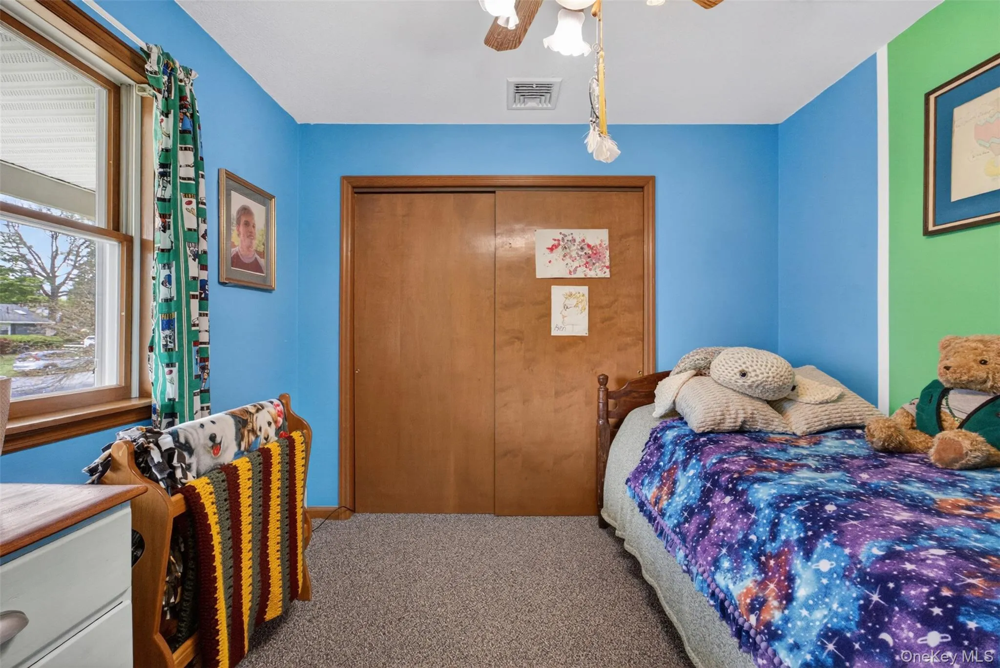 Carpeted room featuring a window with wood trim, a ceiling fan, and a wood-finish closet door Carpeted room featuring a window with wood trim, a ceiling fan, and a wood-finish closet door