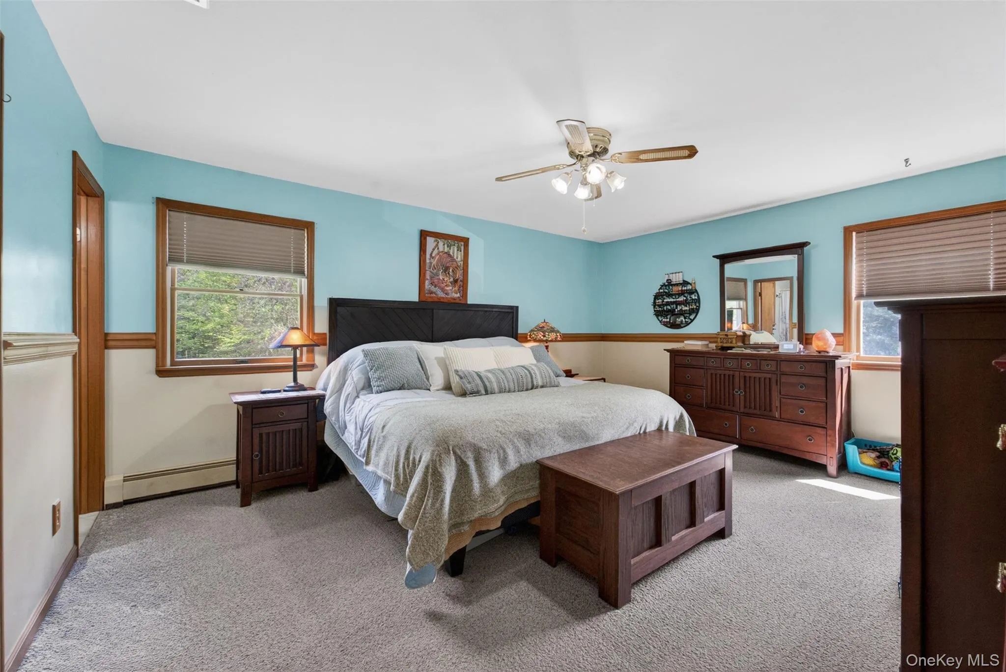 Expansive room featuring light-colored carpeting, two windows with wood trim, and a ceiling fan with integrated lighting Expansive room featuring light-colored carpeting, two windows with wood trim, and a ceiling fan with integrated lighting