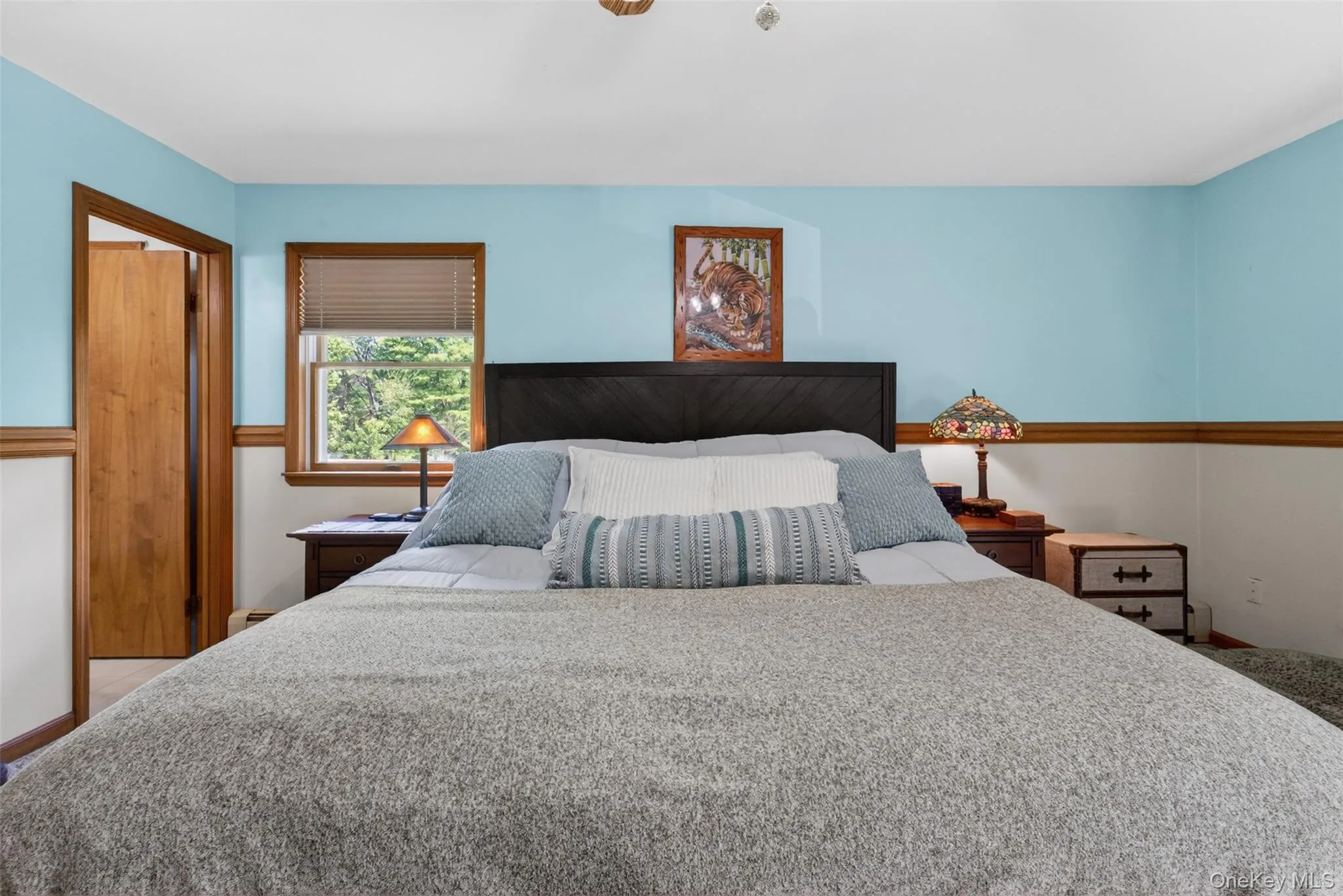 Bedroom featuring a dark wood headboard, wood-framed window with blinds, and light blue walls Bedroom featuring a dark wood headboard, wood-framed window with blinds, and light blue walls