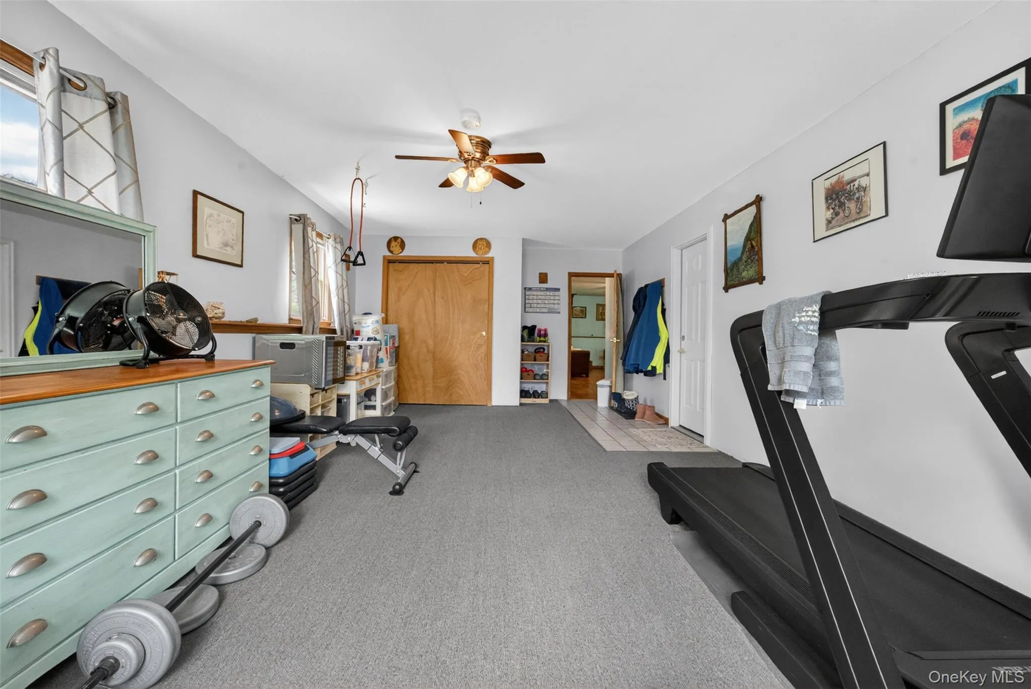 Carpeted room with a ceiling fan, wood finished closet doors, and natural lighting, Access door to Single Car Garage. Carpeted room with a ceiling fan, wood finished closet doors, and natural lighting, Access door to Single Car Garage.