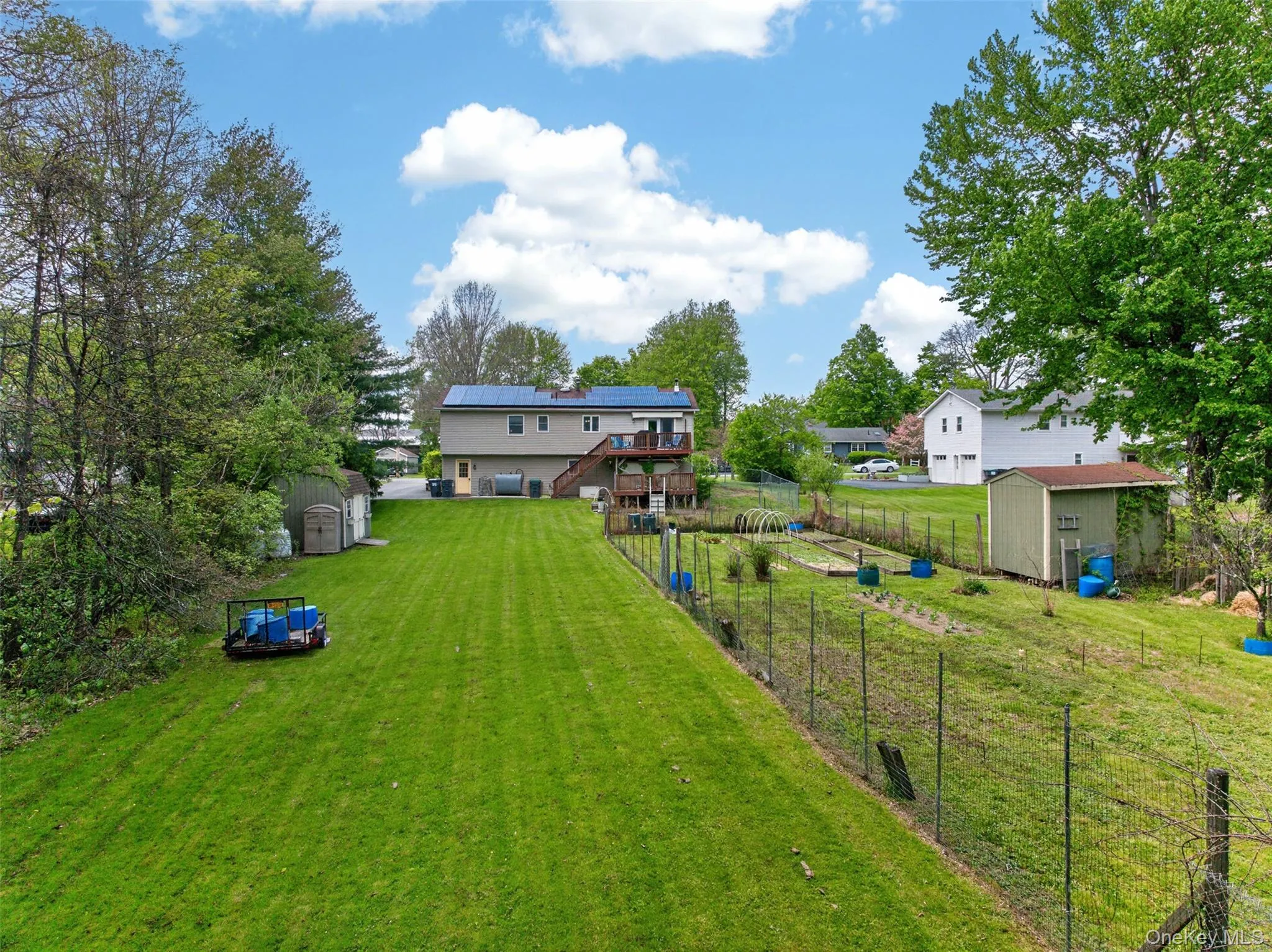 Expansive yard featuring a large grassy area, established garden plots, and two storage sheds Expansive yard featuring a large grassy area, established garden plots, and two storage sheds